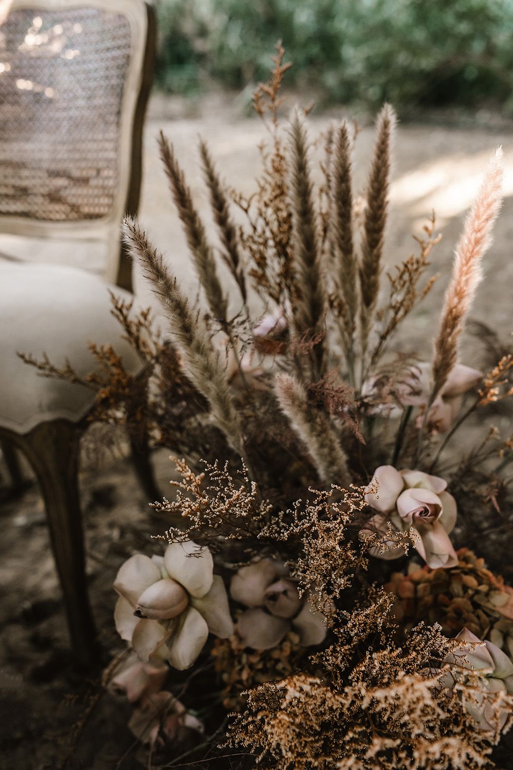 Dried cotton bolls and wheat stalks arranged in a rustic wedding centerpiece.