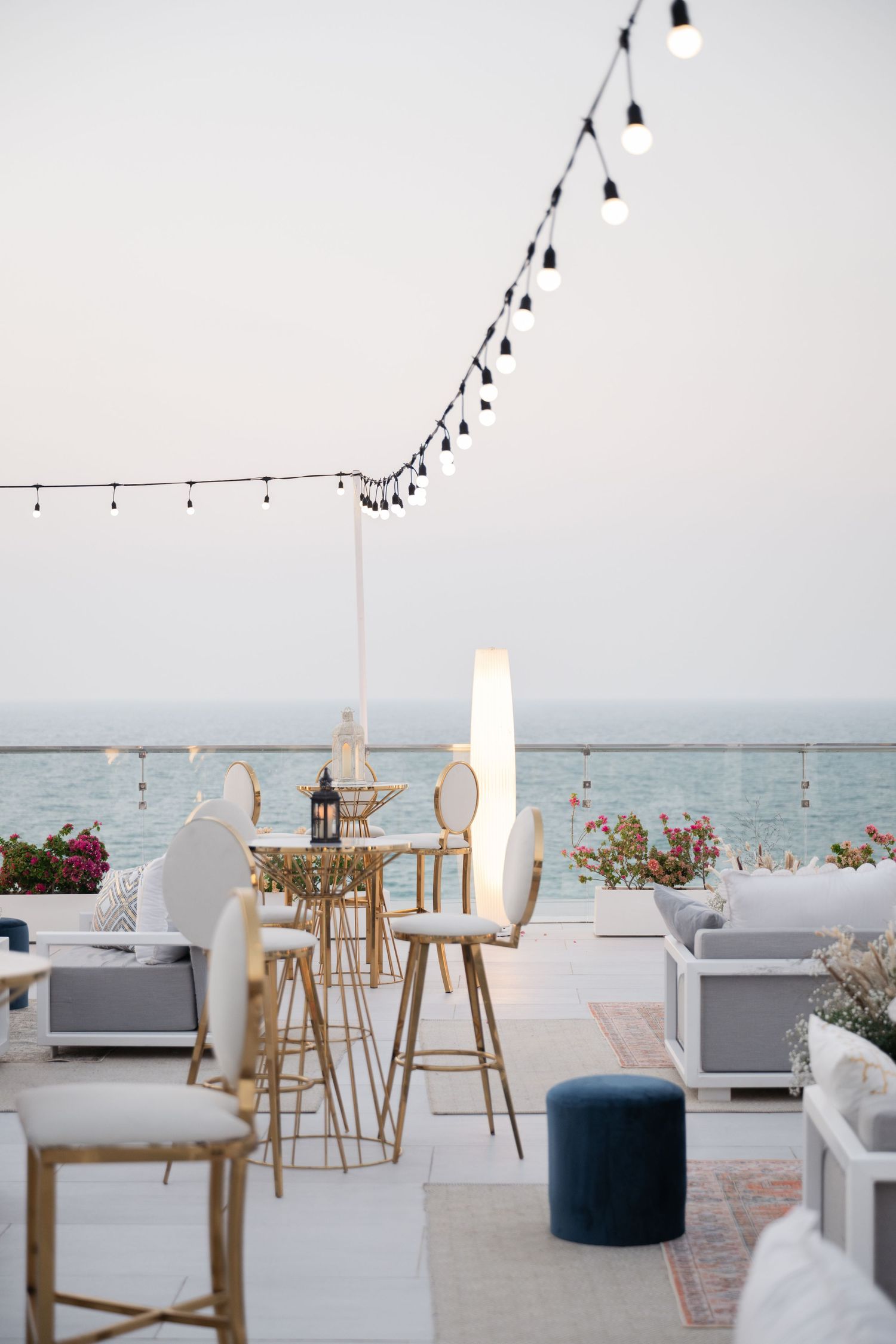 Coastal event space with string lights and modern furniture overlooking ocean view.