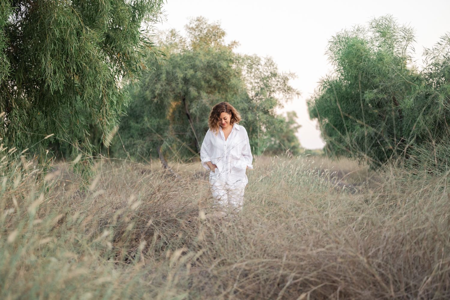 A lady walks through a lush garden path during a golden sunset photo session.
