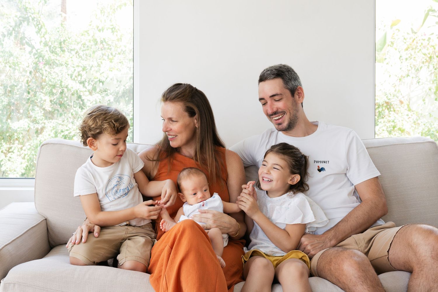 Family relaxing together on comfortable couch in bright living room.