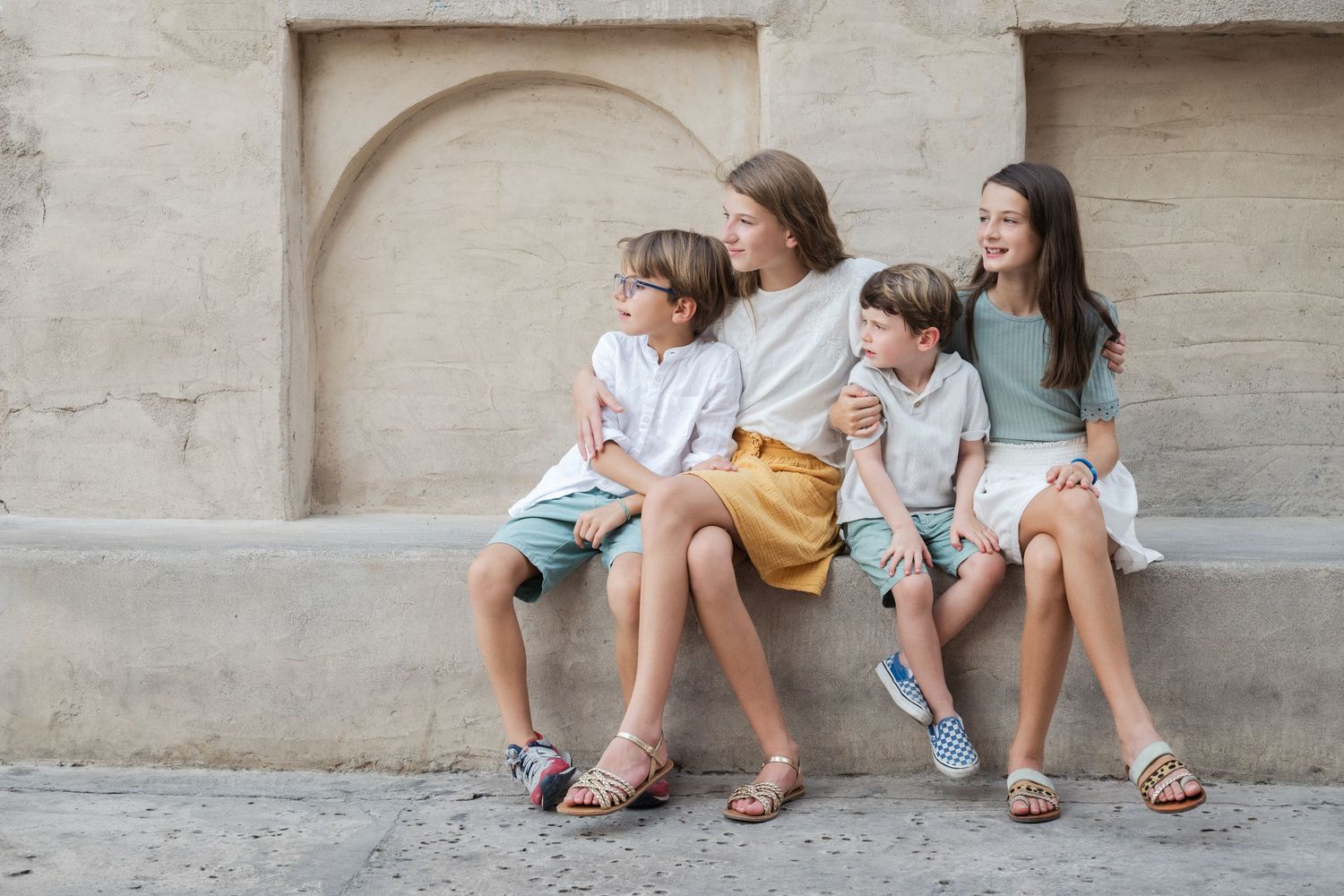 Family sitting together on concrete ledge in casual outdoor setting.