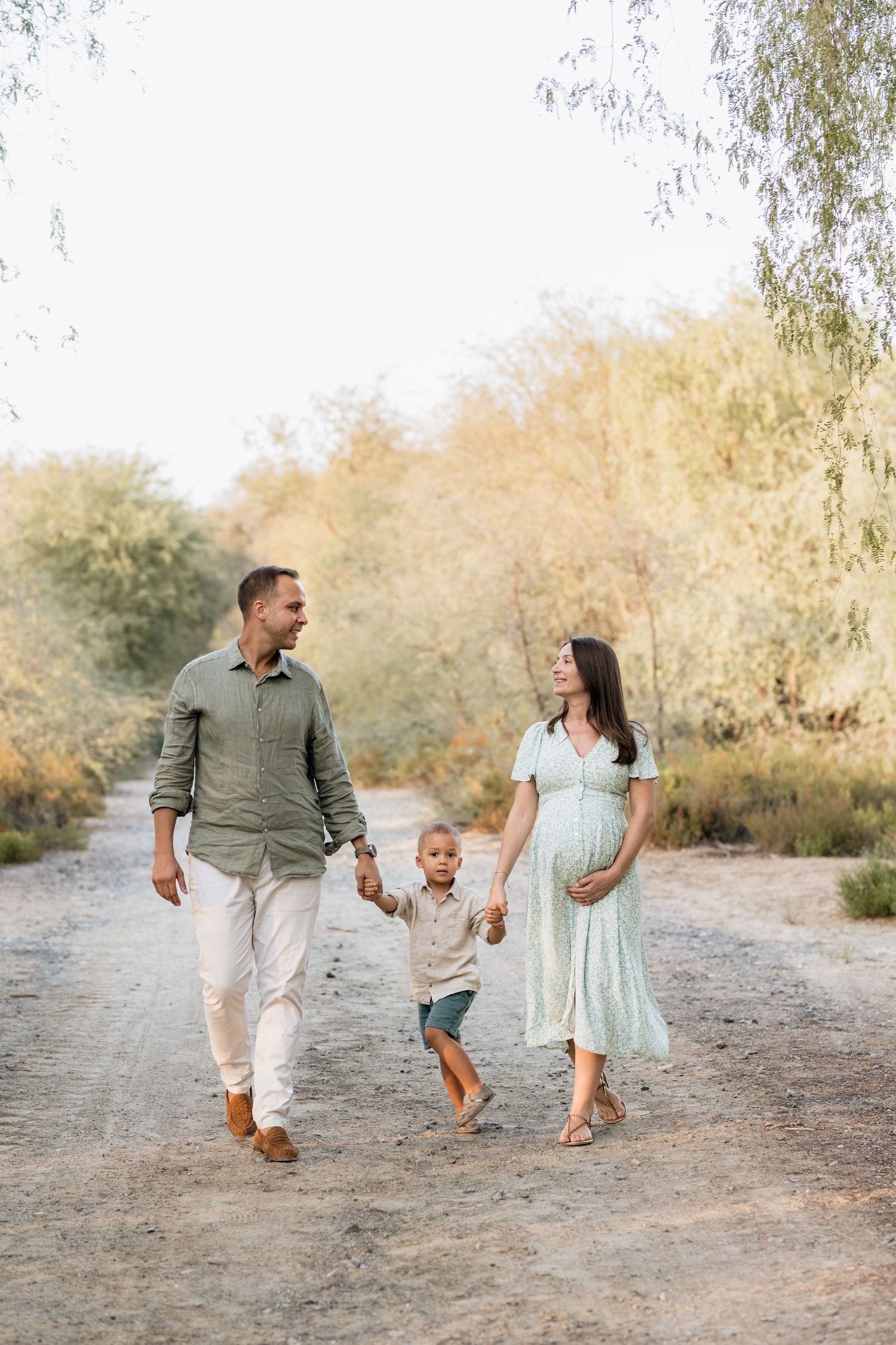 Family walking and playing together on a desert trail during sunset.