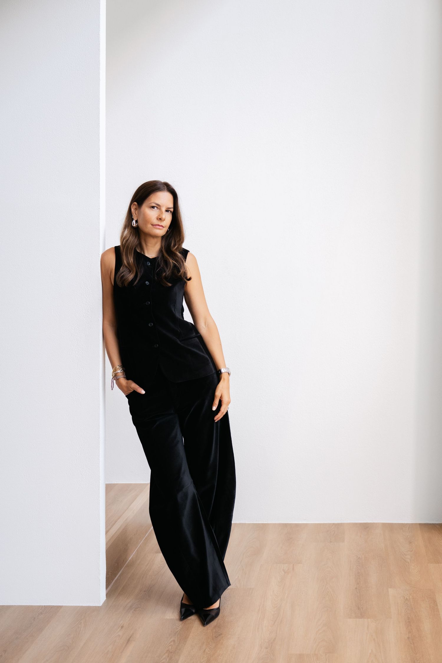 Artistic fashion poses against white wall and wooden floor in all black outfit.