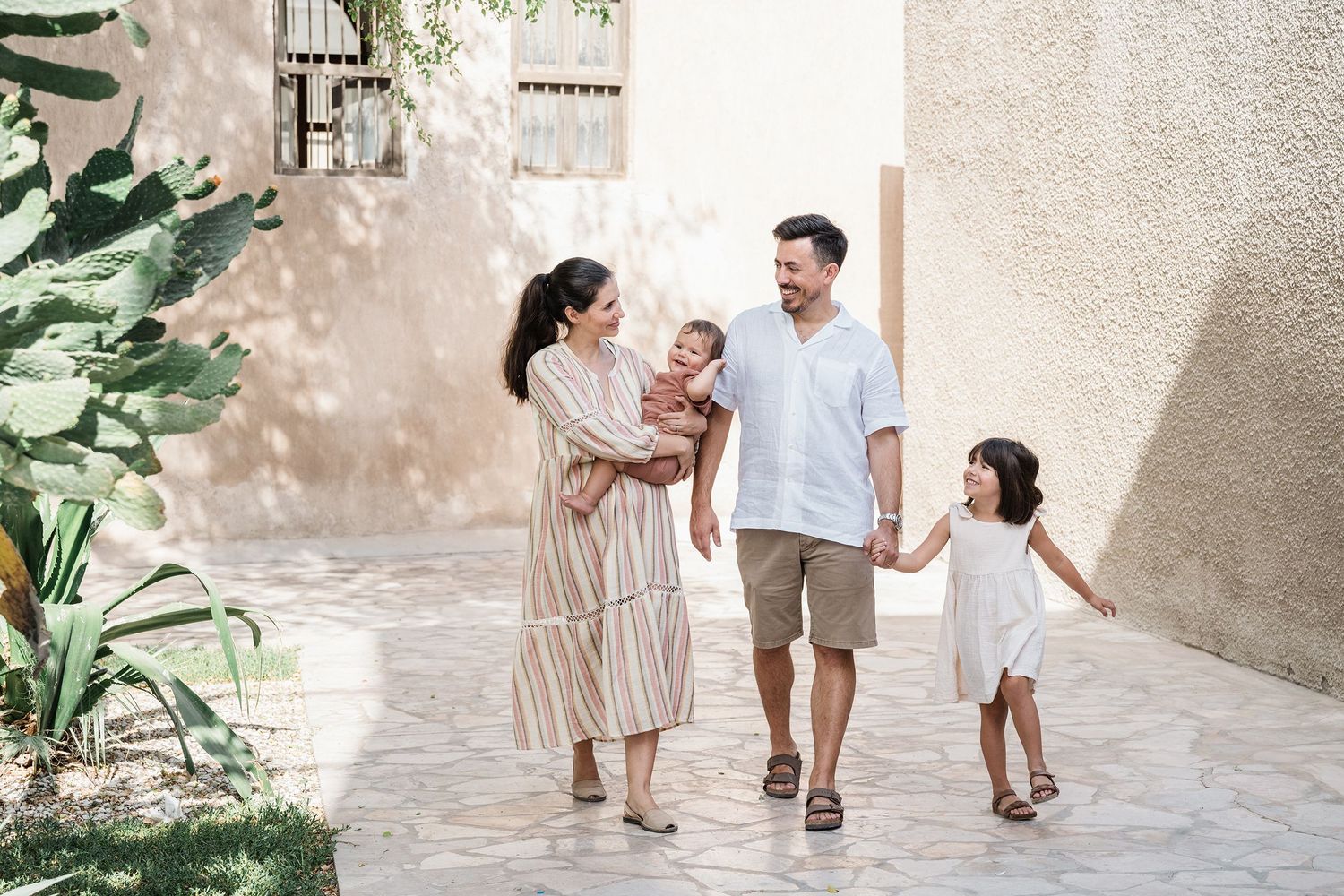 Family walking together through Mediterranean style courtyard with stone walls and greenery.