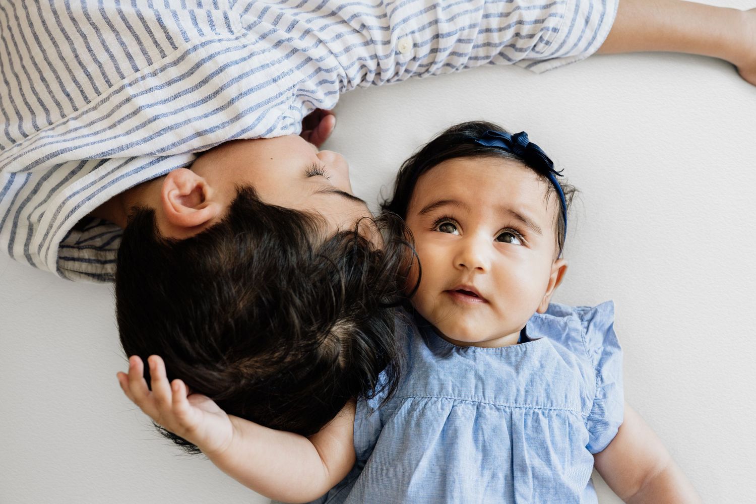 Parents sharing tender moments with their infant on a light background.