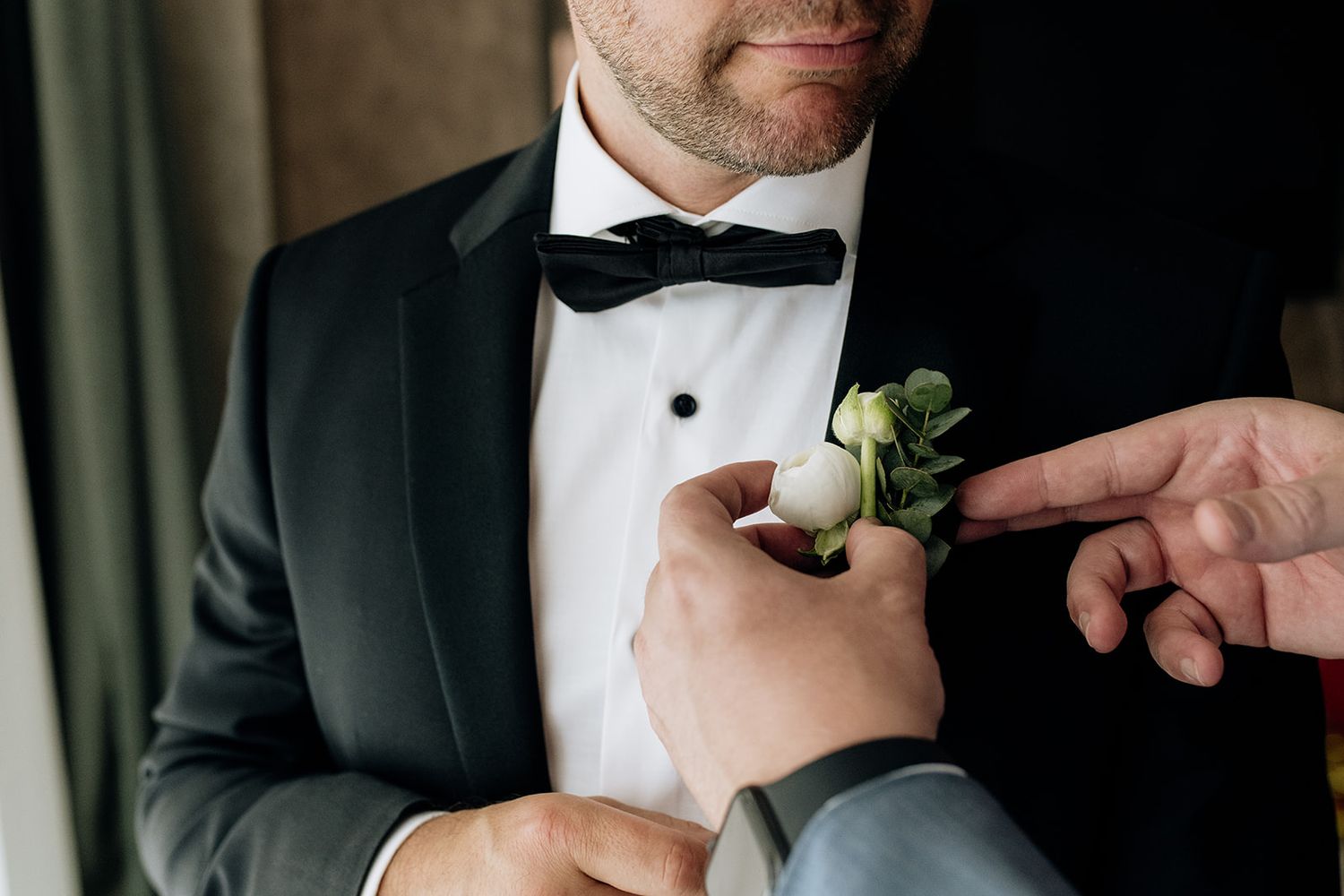 Close-up details of groom's formal attire with boutonniere.