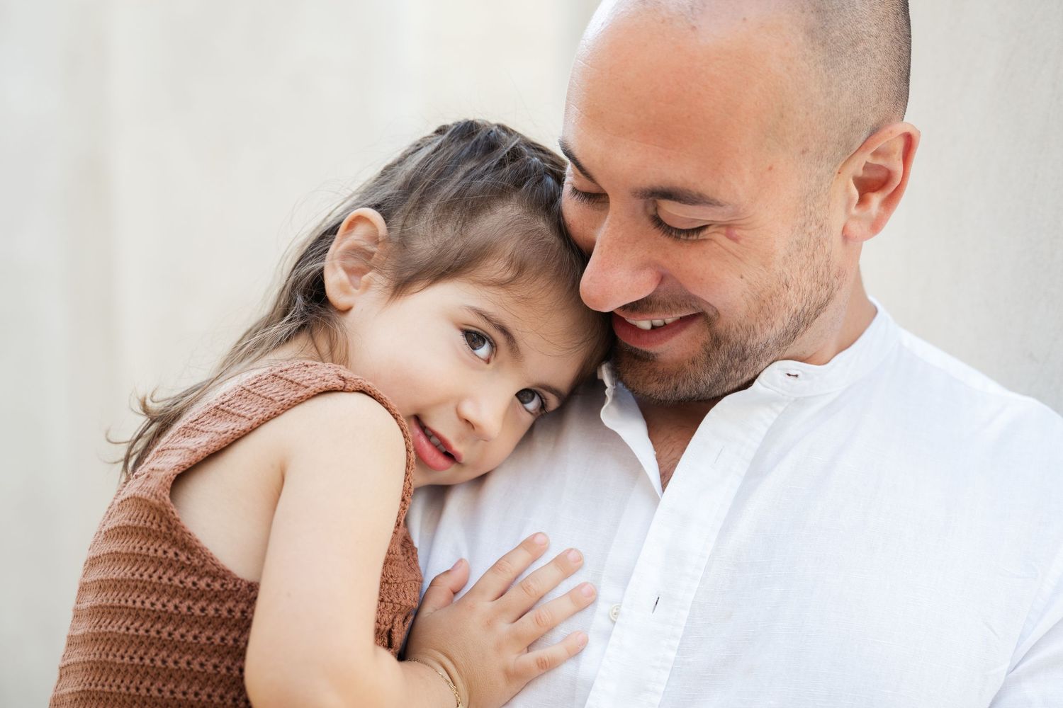 A series of intimate family portraits showing tender moments between parent and child against a light background.
