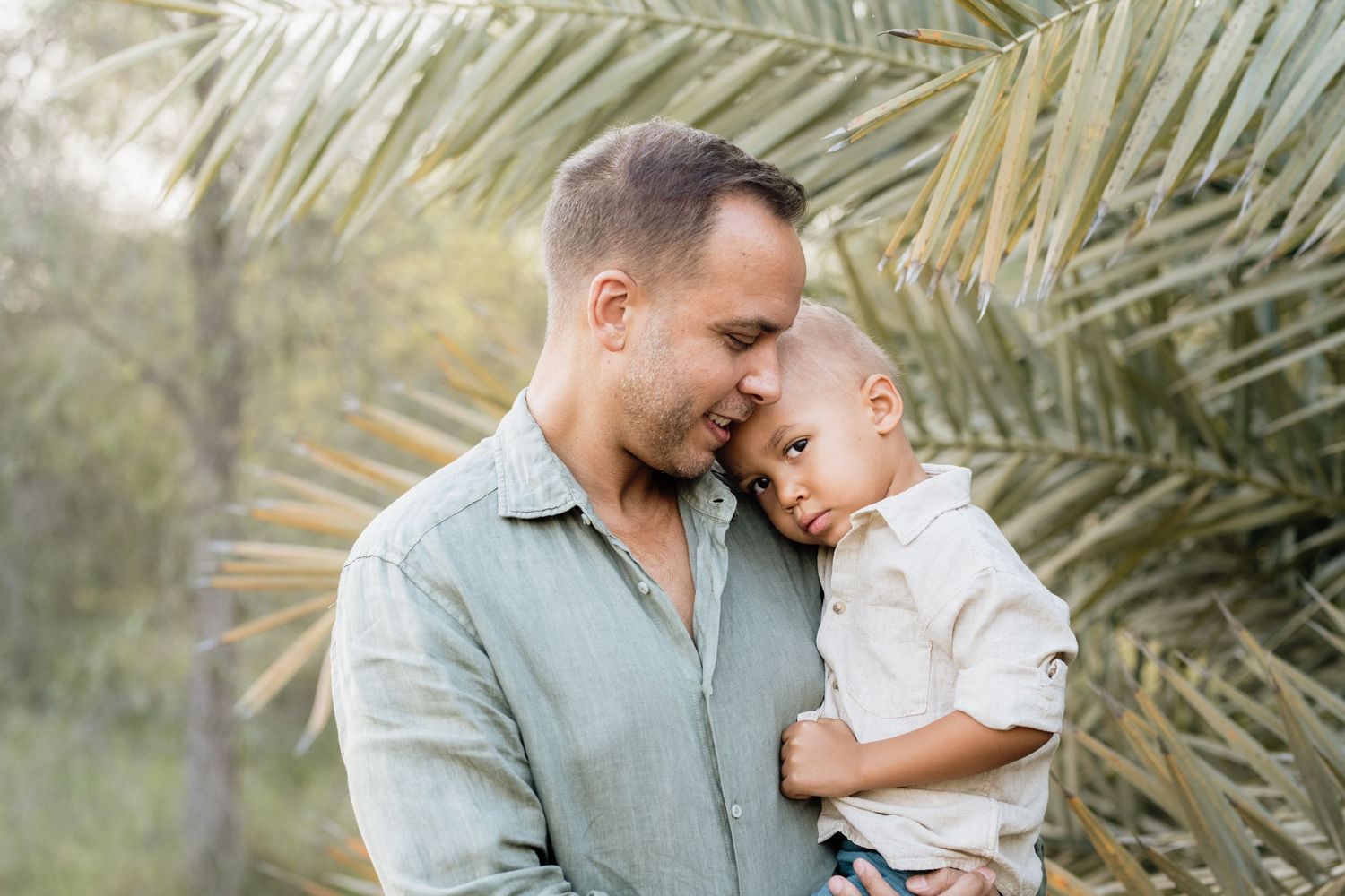 Tender family moments photographed outdoors with palm fronds in the background.