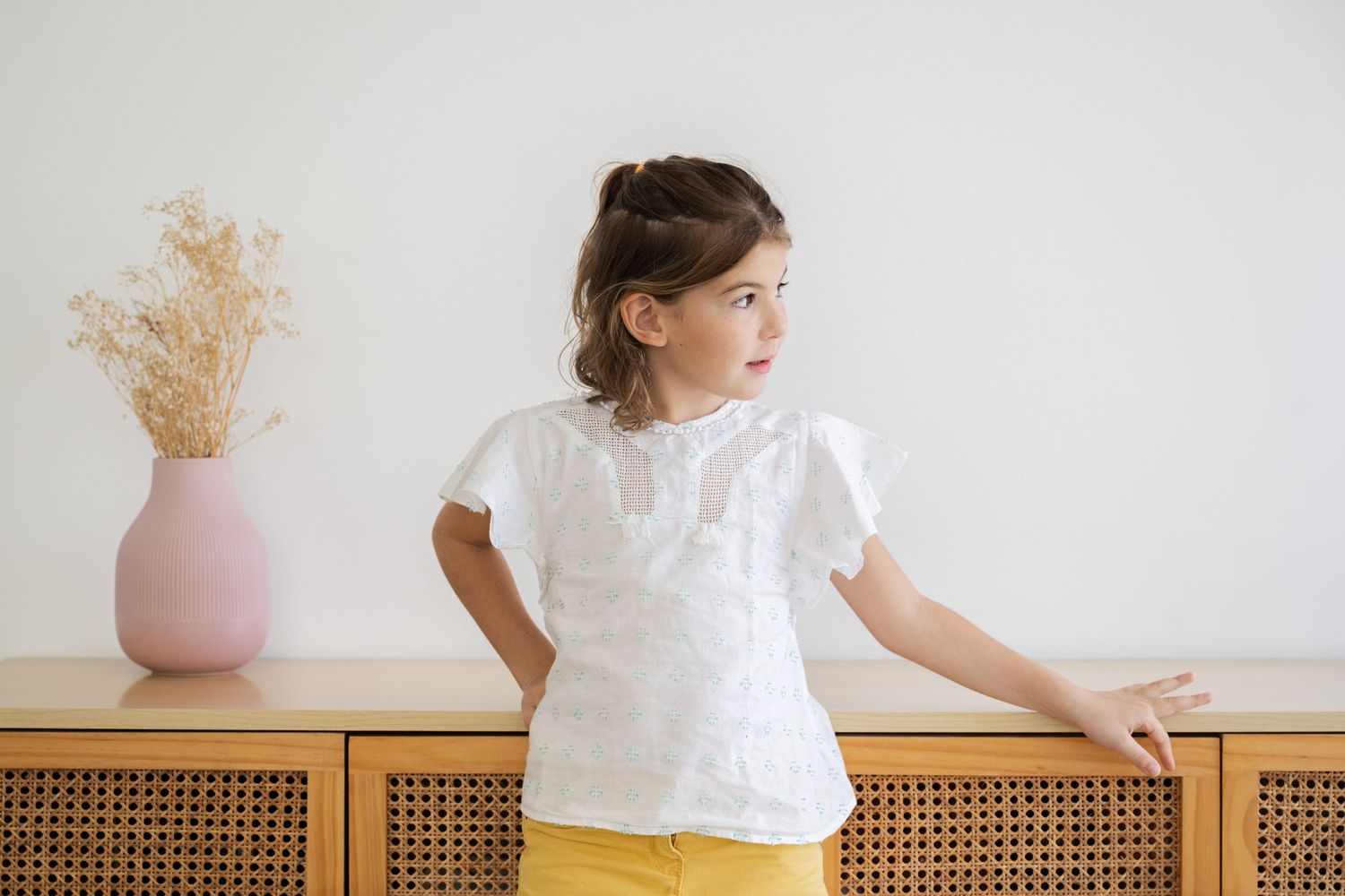 Child exploring and playing on white furniture in minimalist room setting.