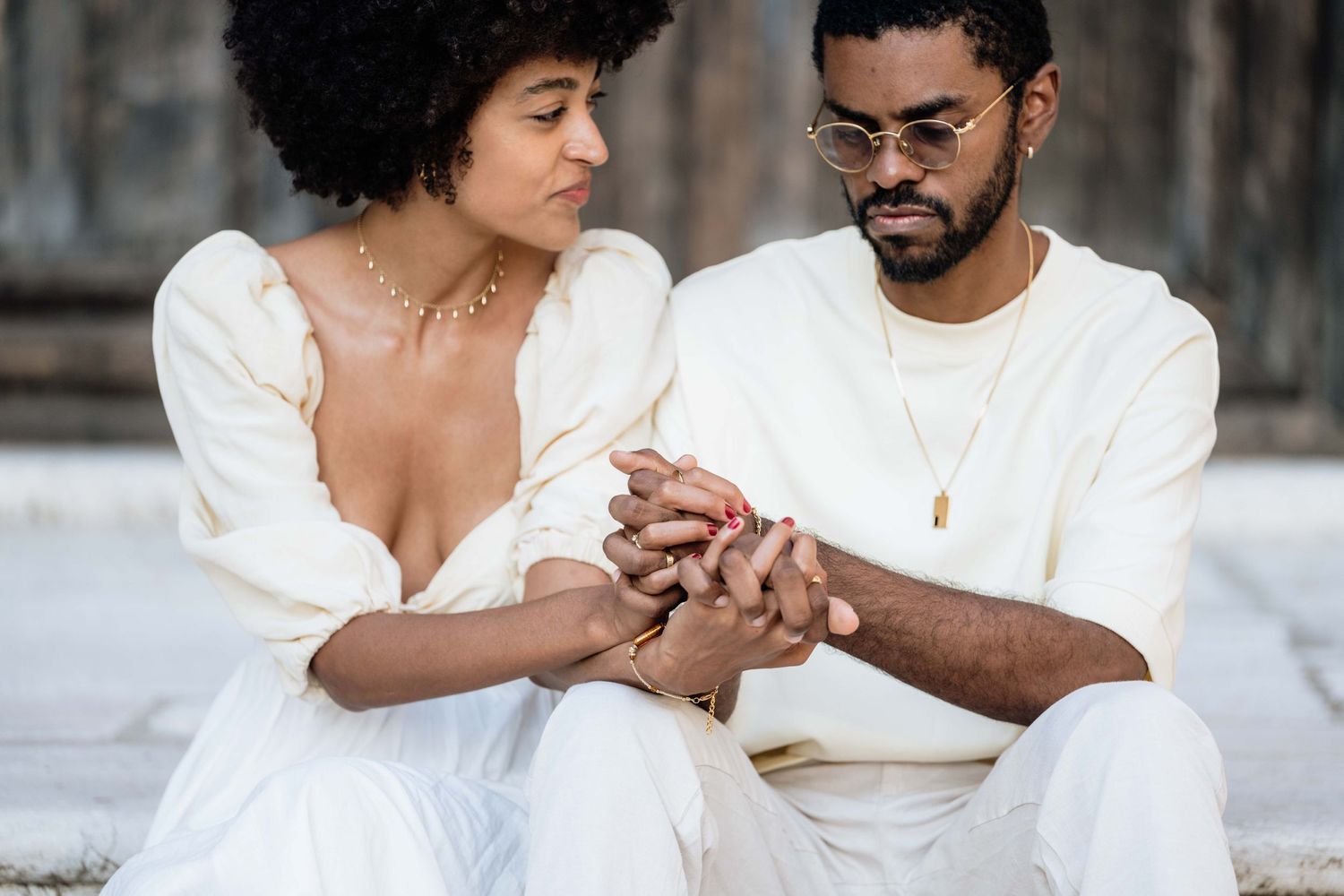 An intimate moment captured as a couple holds hands while sitting on stone steps.