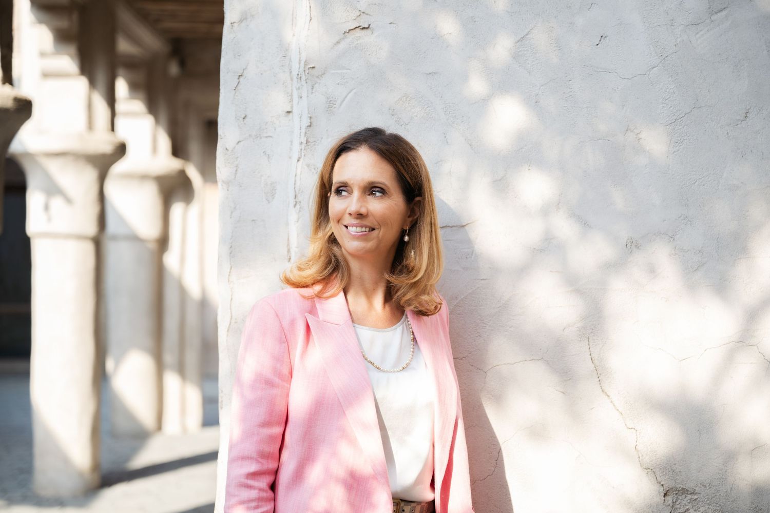 Professional branding photos with pink blazer in outdoor architectural setting.
