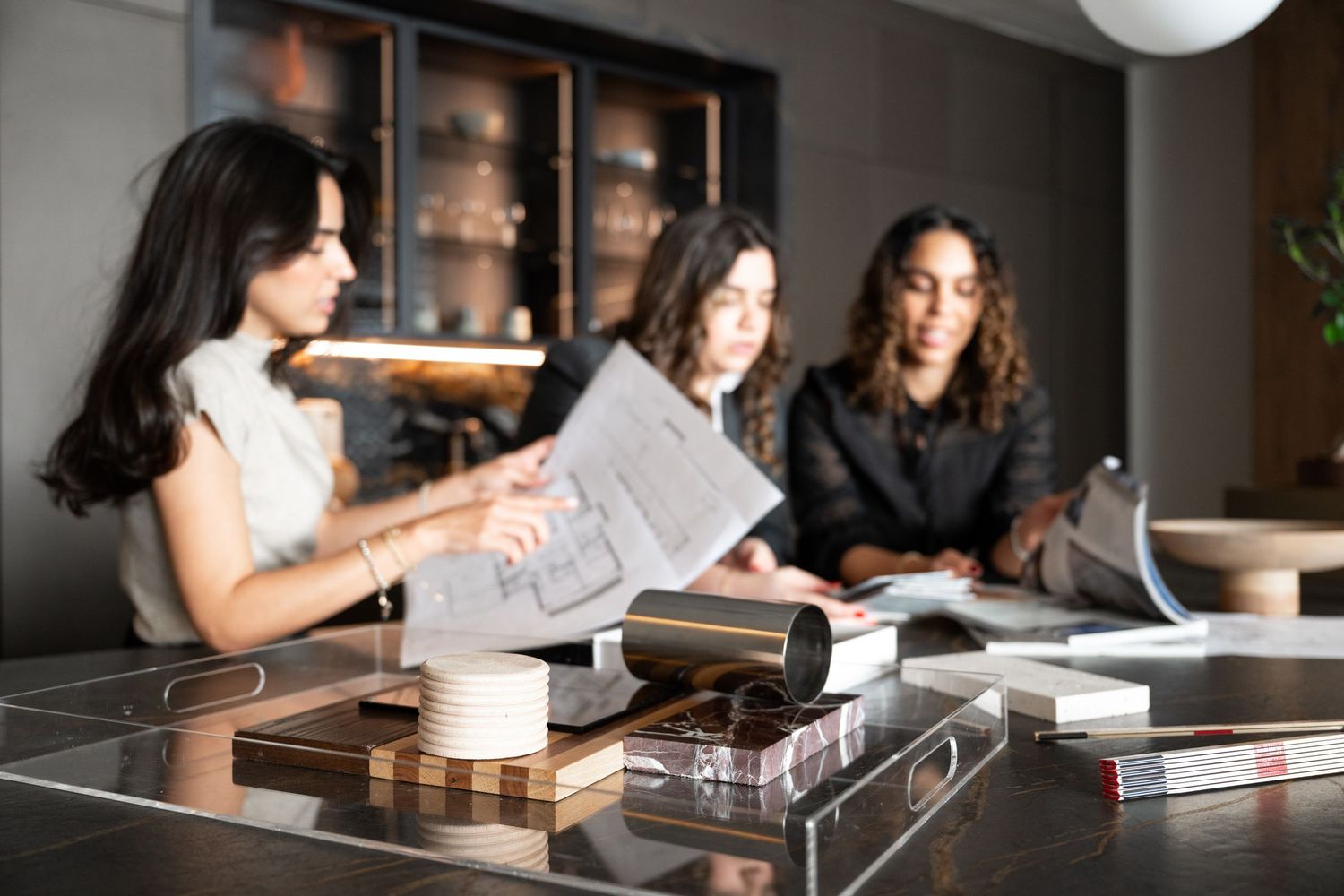 Group meeting in modern office space with coffee and documents on table.