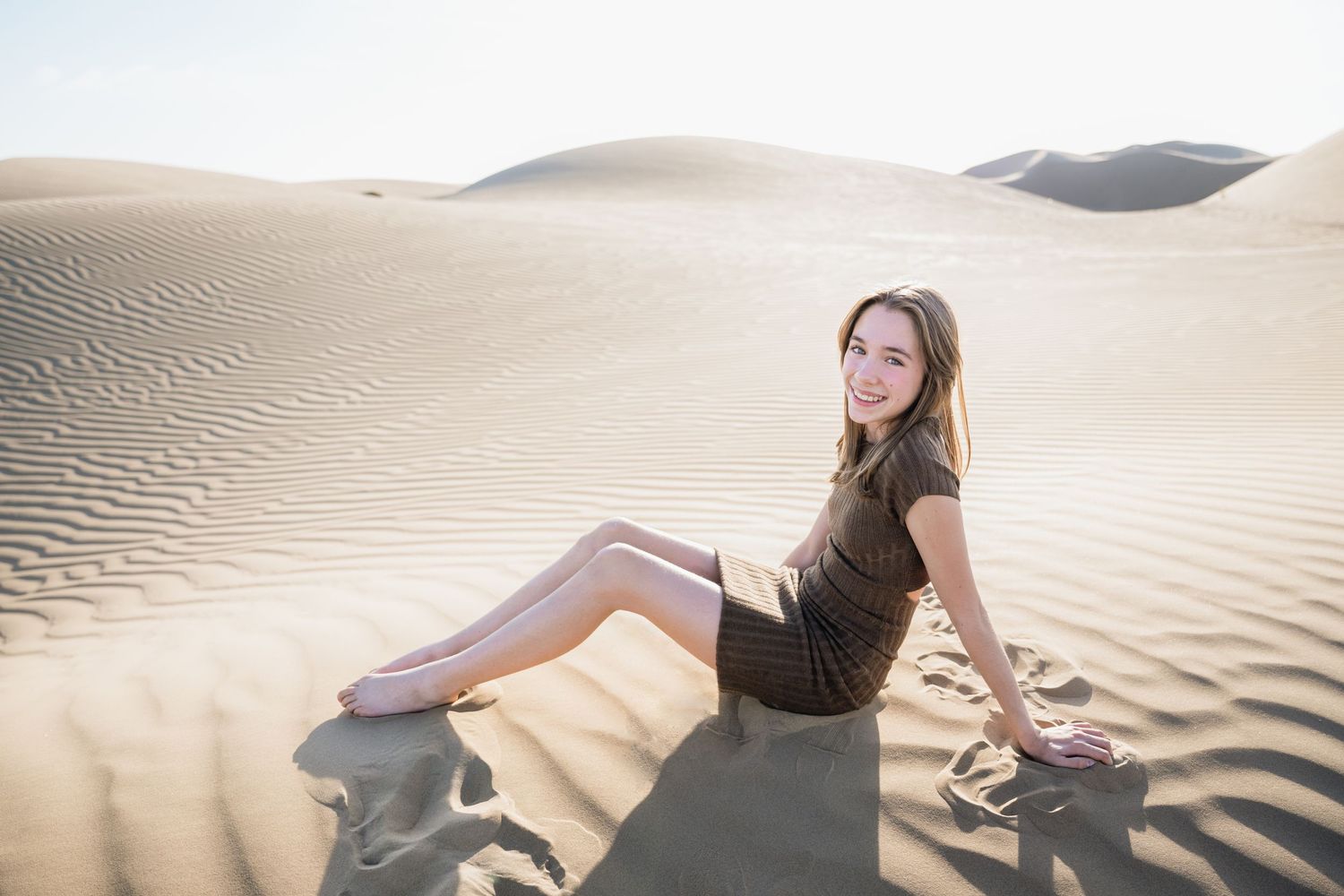People relaxing on sandy slopes during desert photoshoot session.