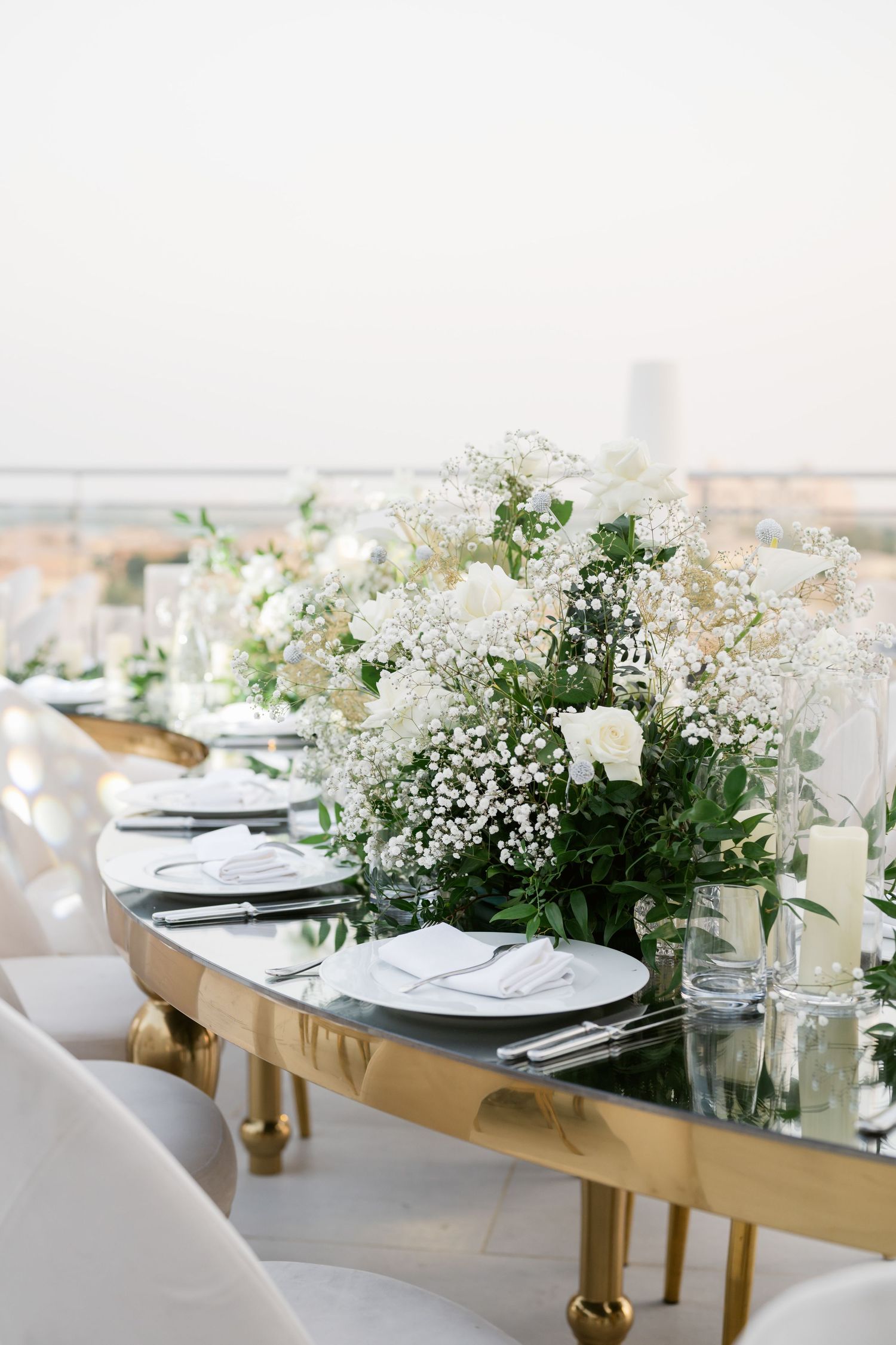 Elegant table setting with white floral centerpieces and gold accents for upscale event.