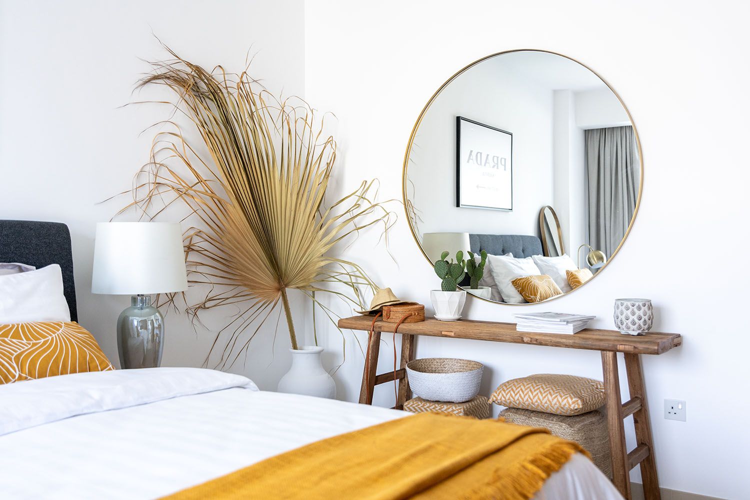 Boho-inspired bedroom corner with rattan decor, round mirror, and natural elements.