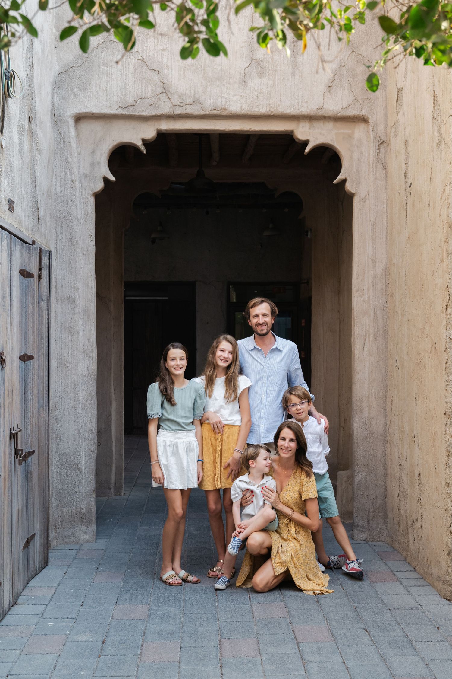 A family photo session in an arched stone hallway with natural lighting.