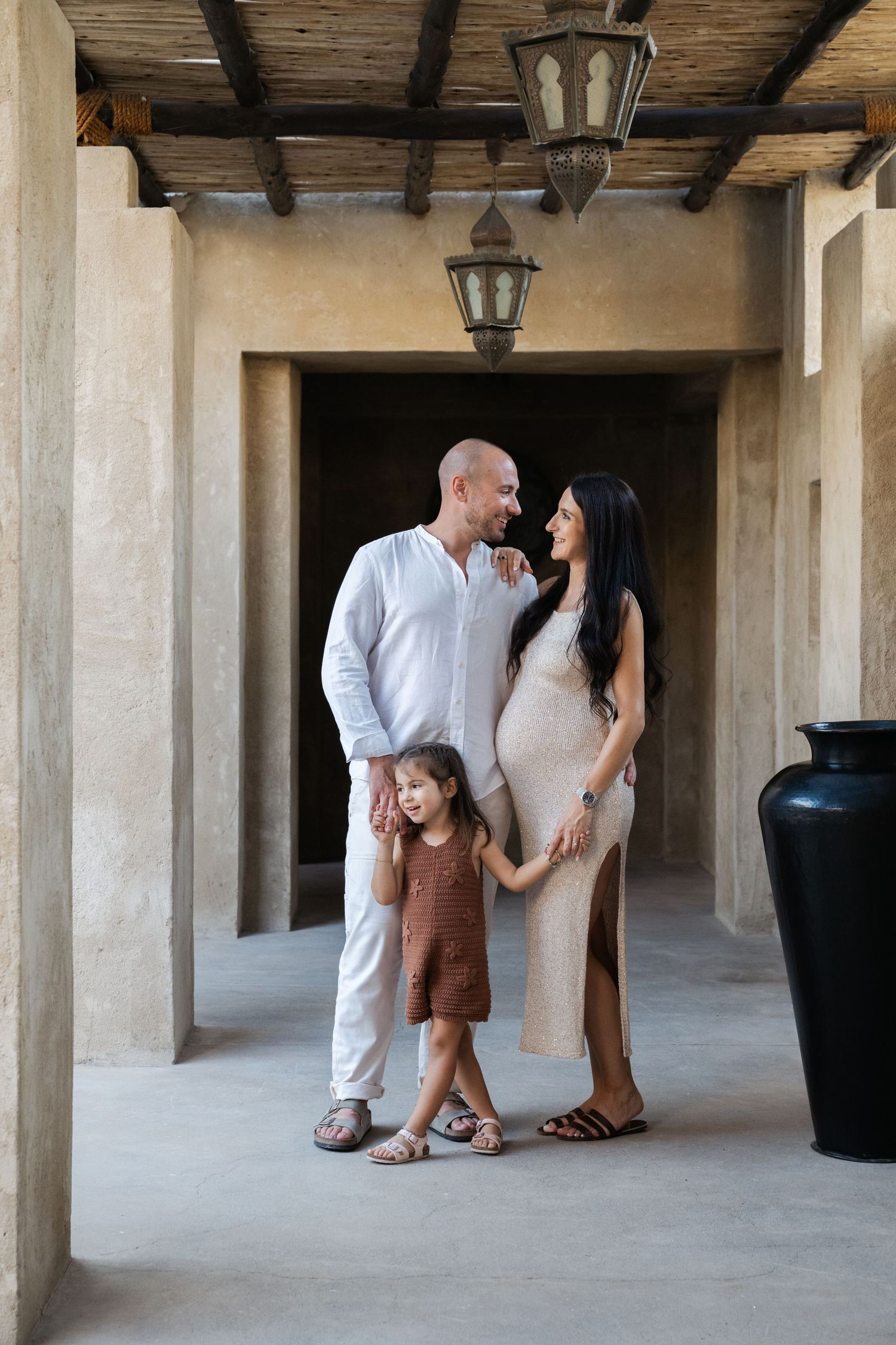Family maternity photos taken under rustic wooden beams and columns.