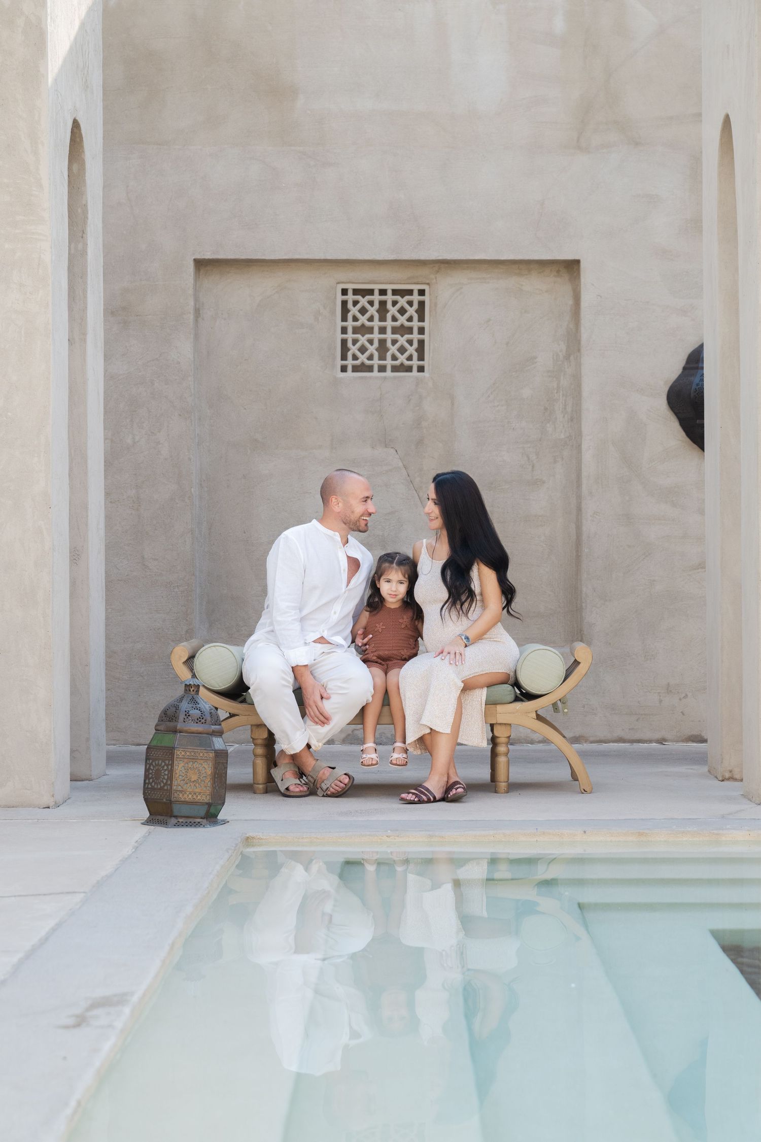 Family photoshoot in a modern architectural setting with white columns and a reflective pool.