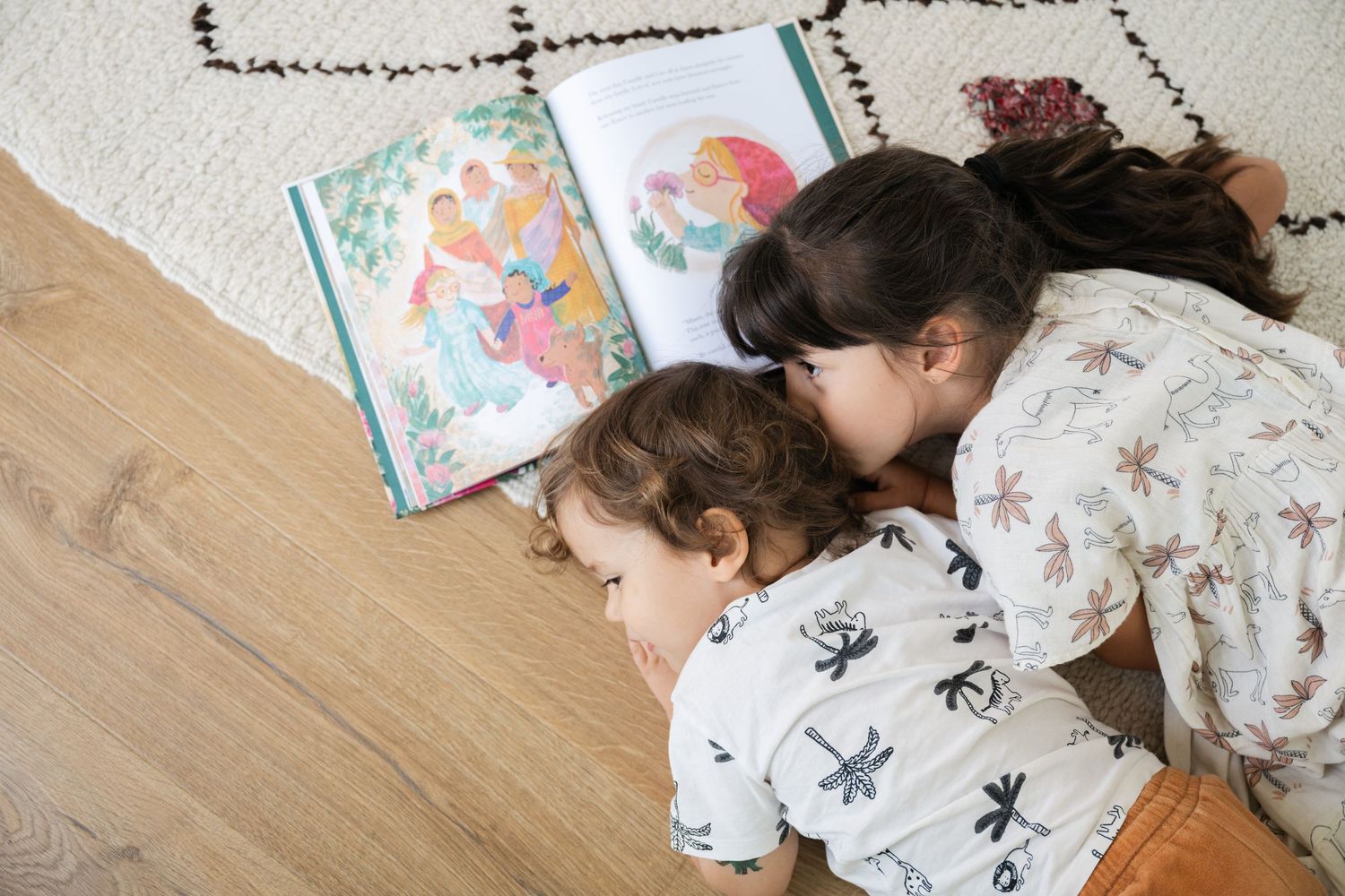 Child lying on floor reading books with scattered pages around.