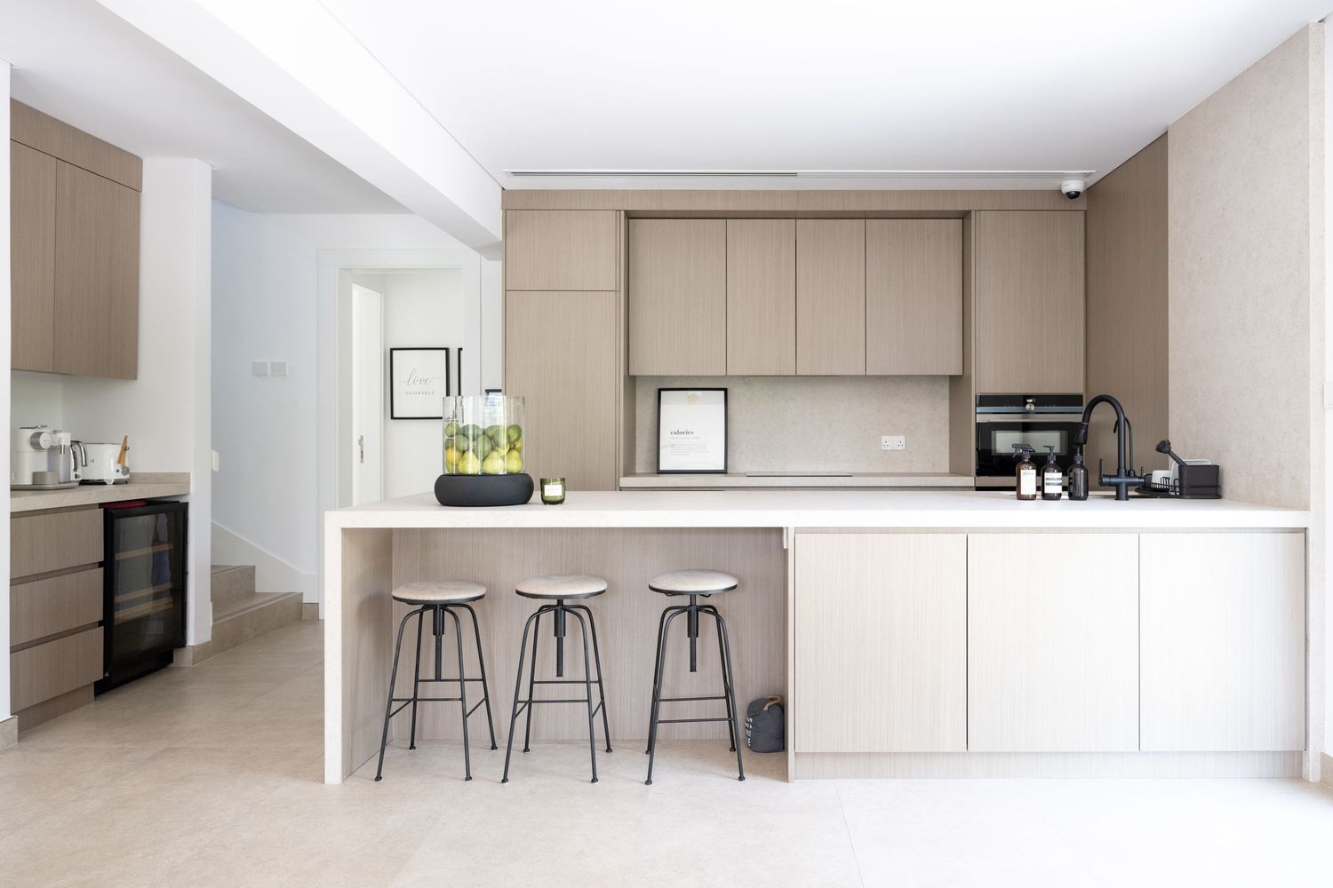 Sleek modern kitchen design with beige cabinetry and minimalist bar seating.