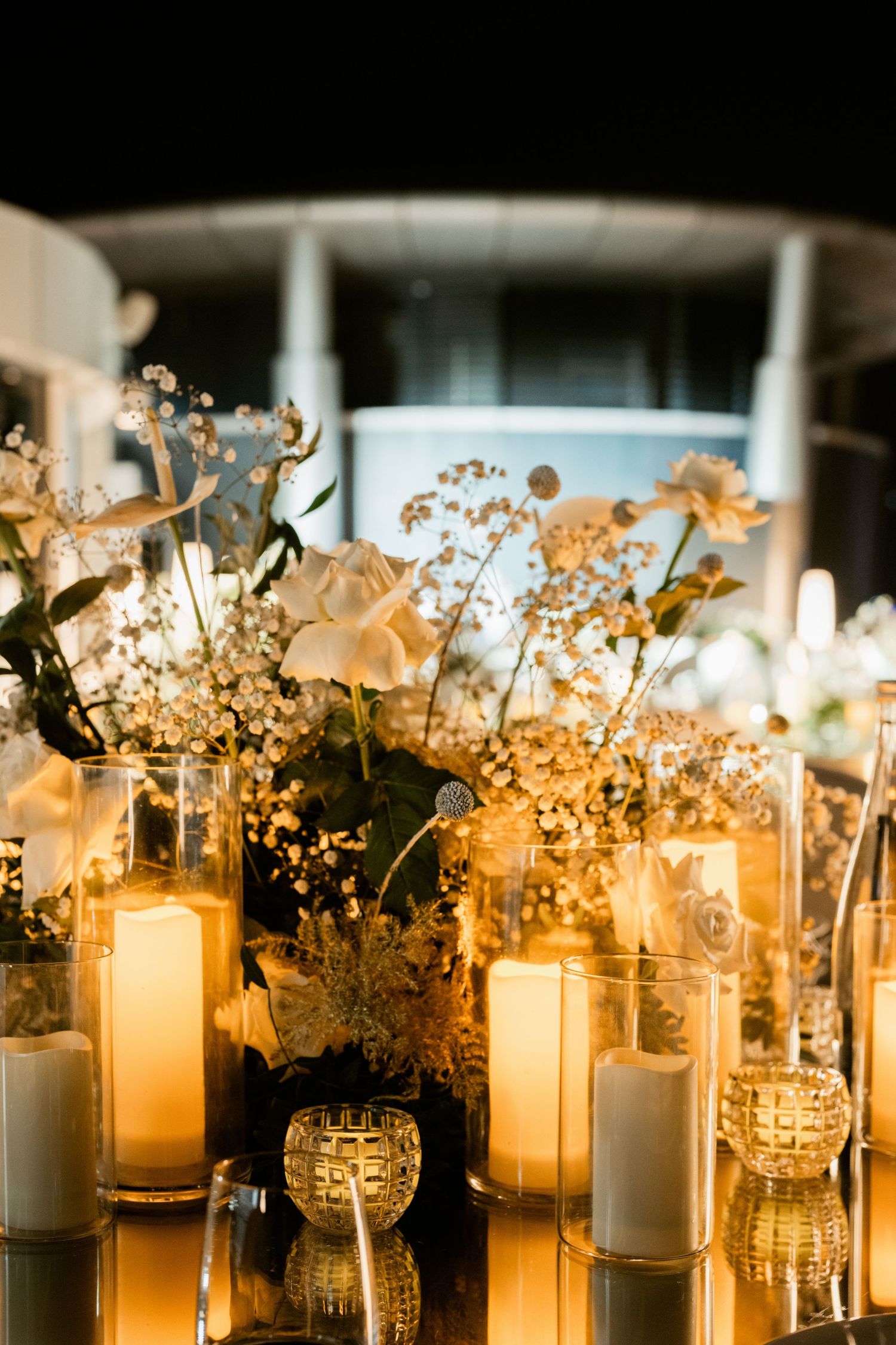 Romantic candlelit table decor with baby's breath flowers in glass vases glowing at night.