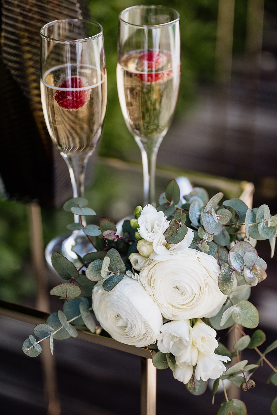 Wedding champagne flutes displayed with white roses and eucalyptus arrangements.