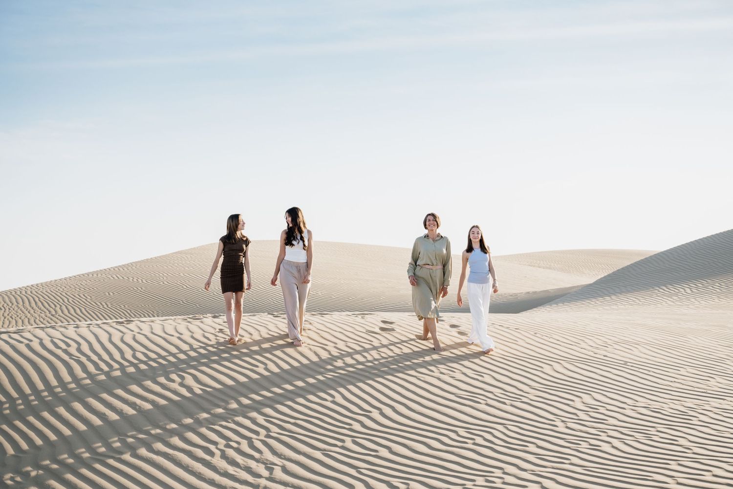 Small group walking along sandy ridges in desert landscape.