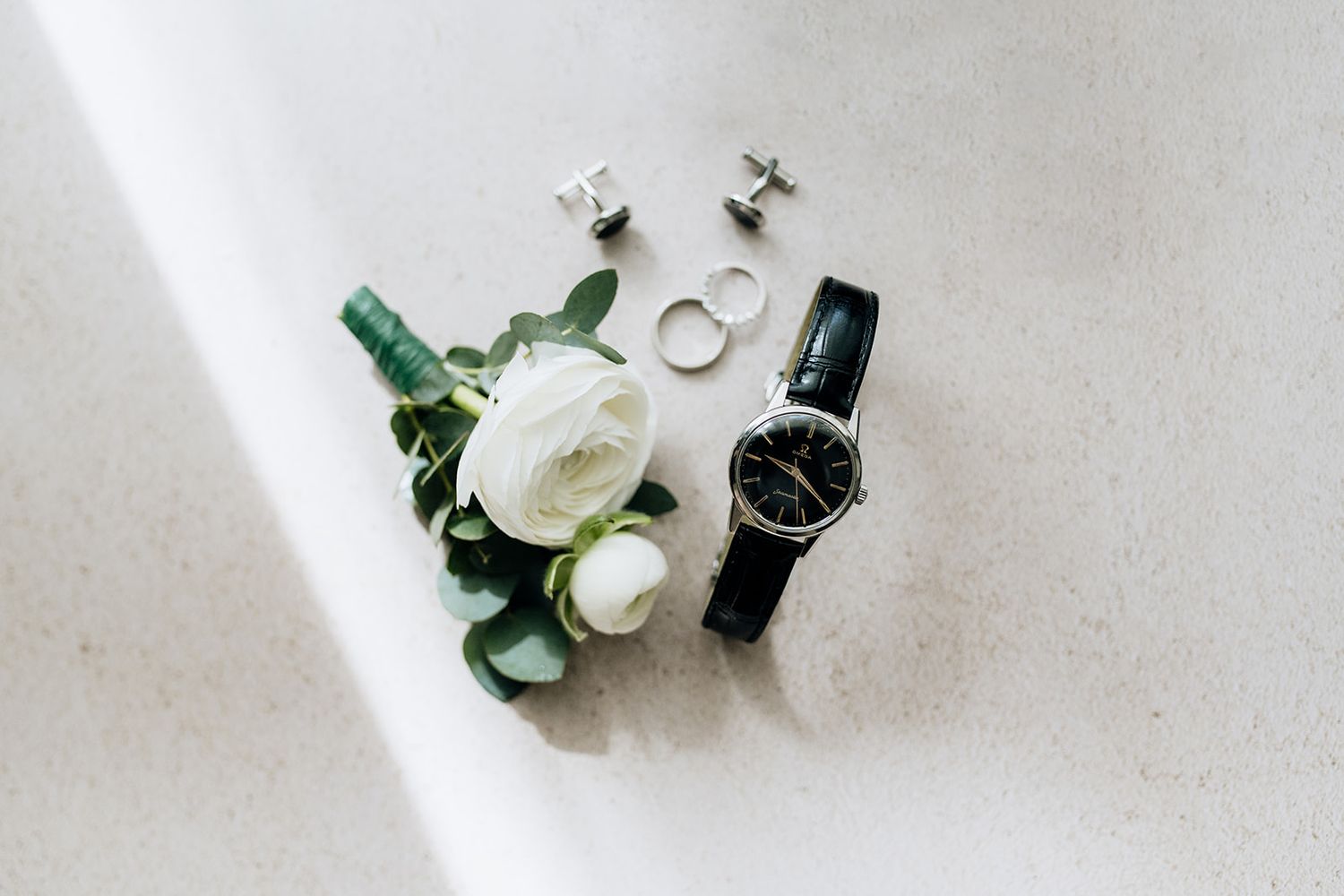 White roses and wedding rings displayed on a light surface with delicate floral details.