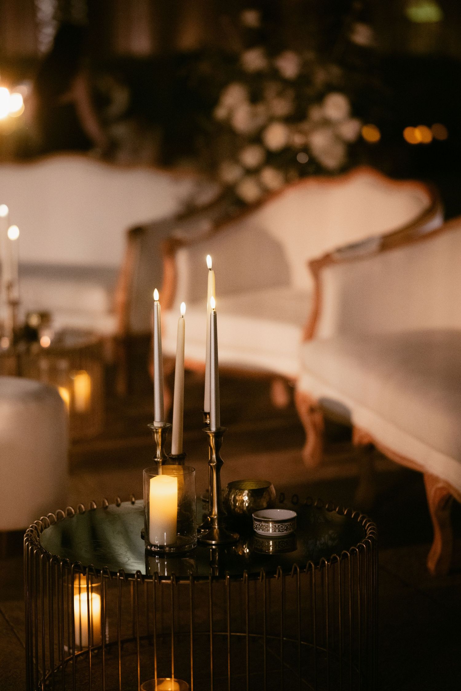 Moody candlelit wedding reception decor with white taper candles and elegant table settings.