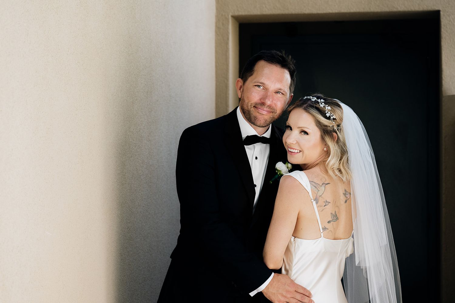 Romantic wedding portraits captured in dramatic doorway lighting.