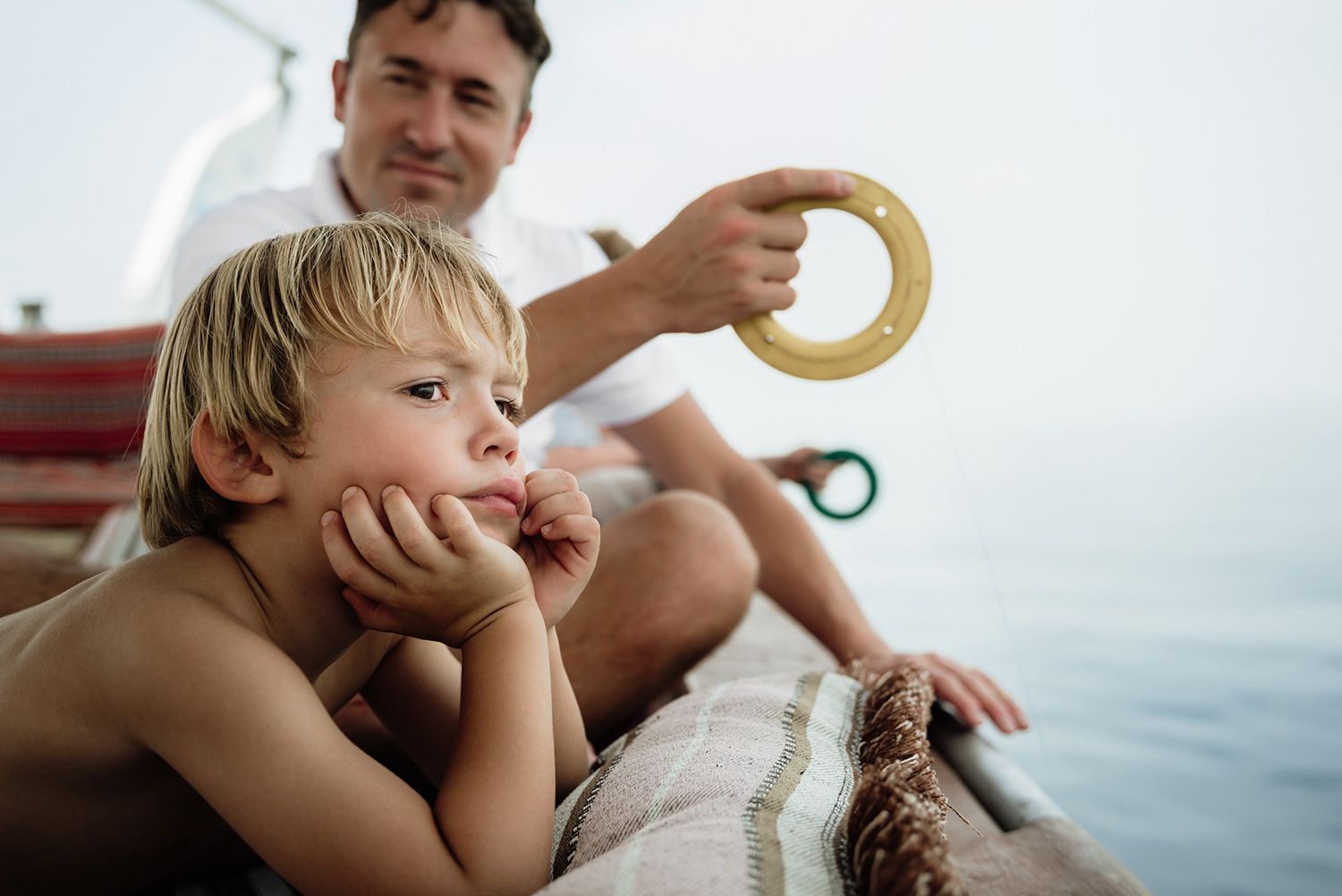 A person holds a banana-shaped toy in front of a child near the water.