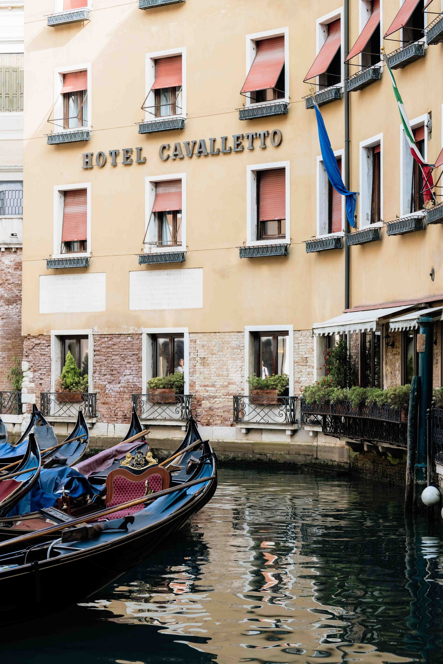 Hotel Cavalletto facade with traditional gondolas moored along Venice canal.