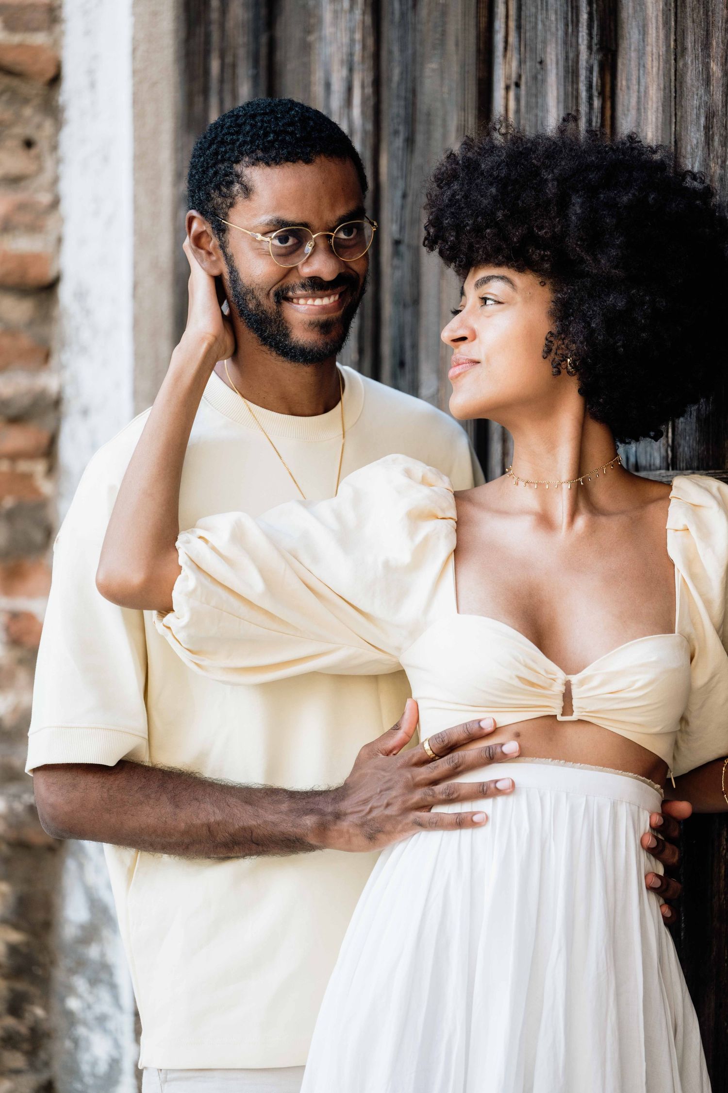 Couple in matching cream outfits share loving glances during a romantic photoshoot.