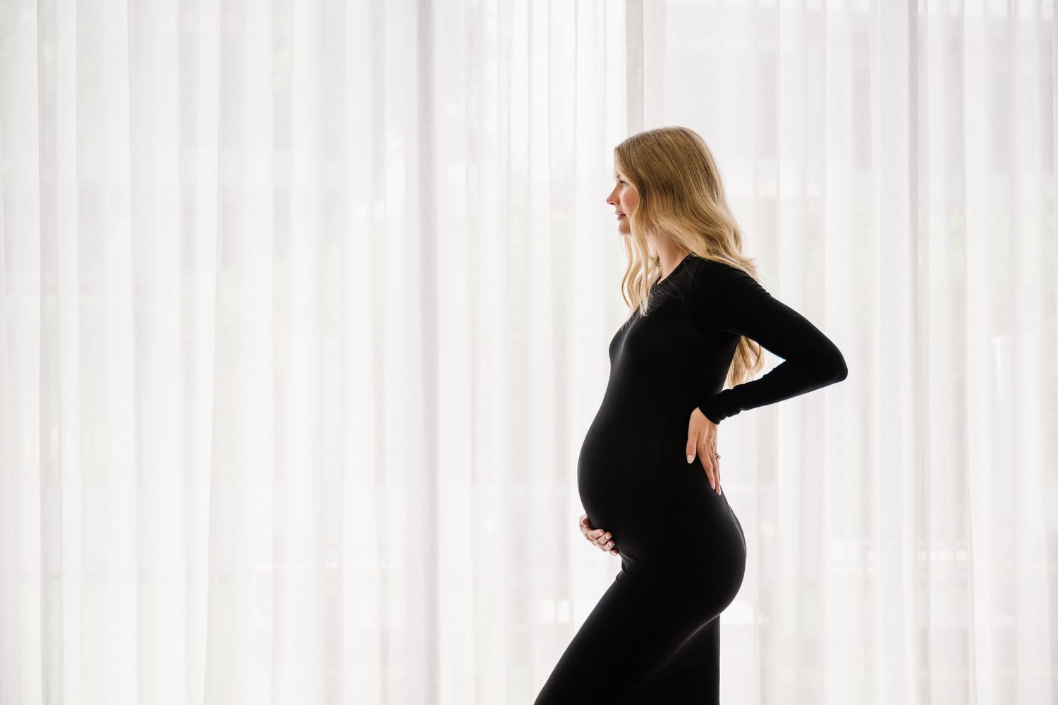 Silhouette progression of pregnant woman in black against white backdrop.