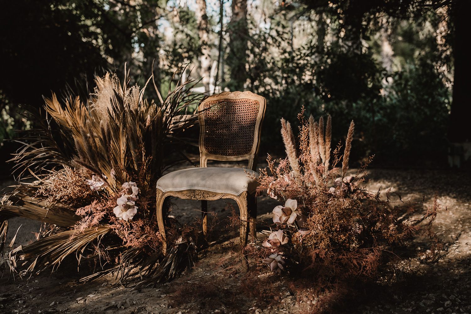 Rustic outdoor wedding decor with dried pampas grass and natural elements in warm sunlight.