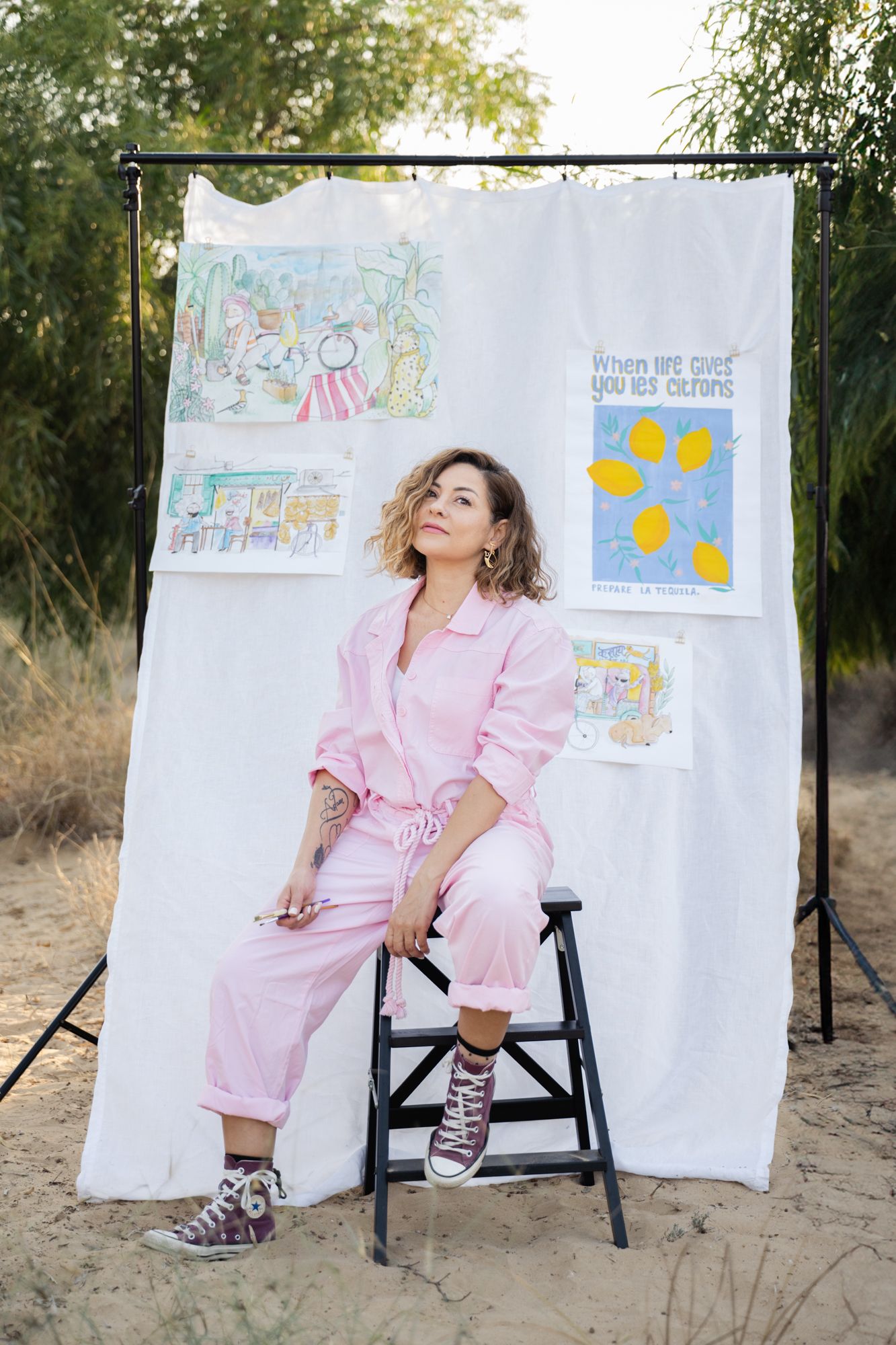 Artistic outdoor photo session featuring pink outfit against white backdrop with artworks displayed.