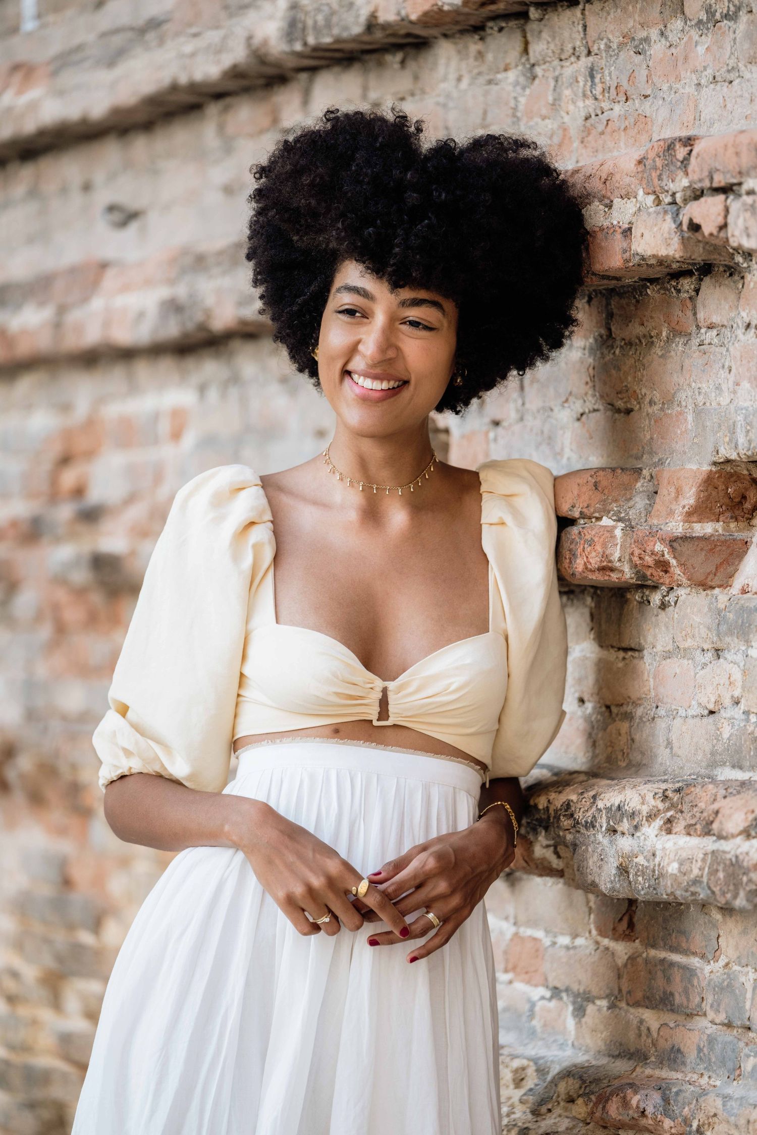 A joyful moment captured against exposed brick with natural lighting and white attire.