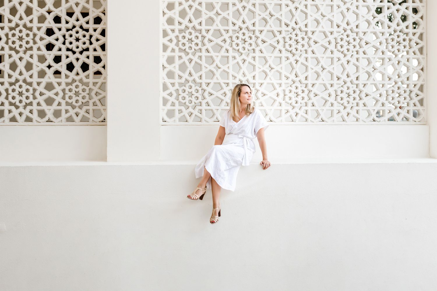 A series of photos showing someone in a white dress posing against a decorative wall with geometric patterns.