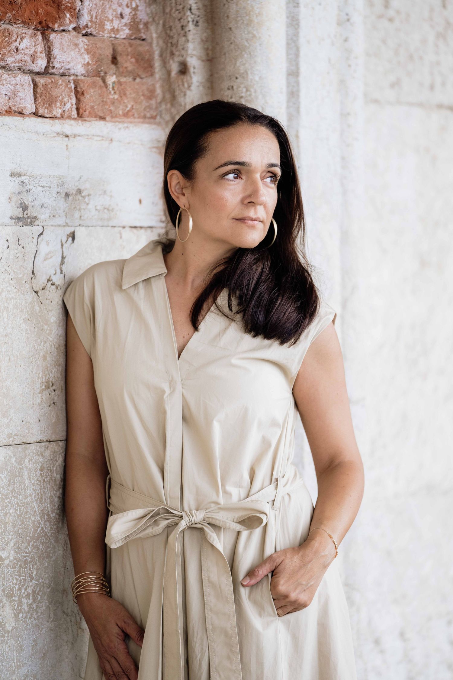 Beige dress with tie detail photographed against weathered Venetian brick and stone walls.