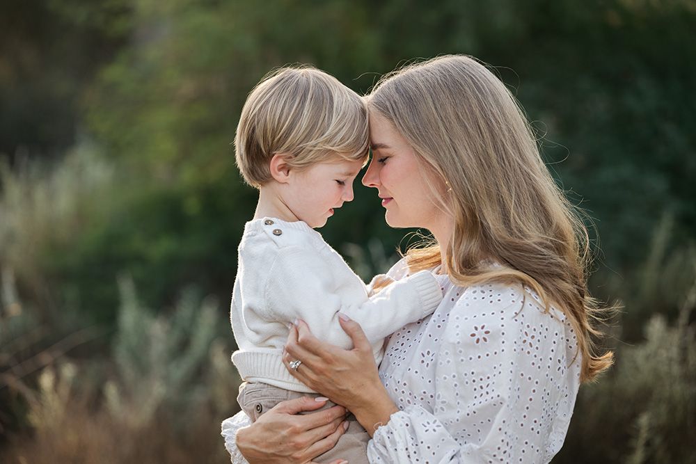 A tender moment captured outdoors with soft natural lighting and white lace clothing details.