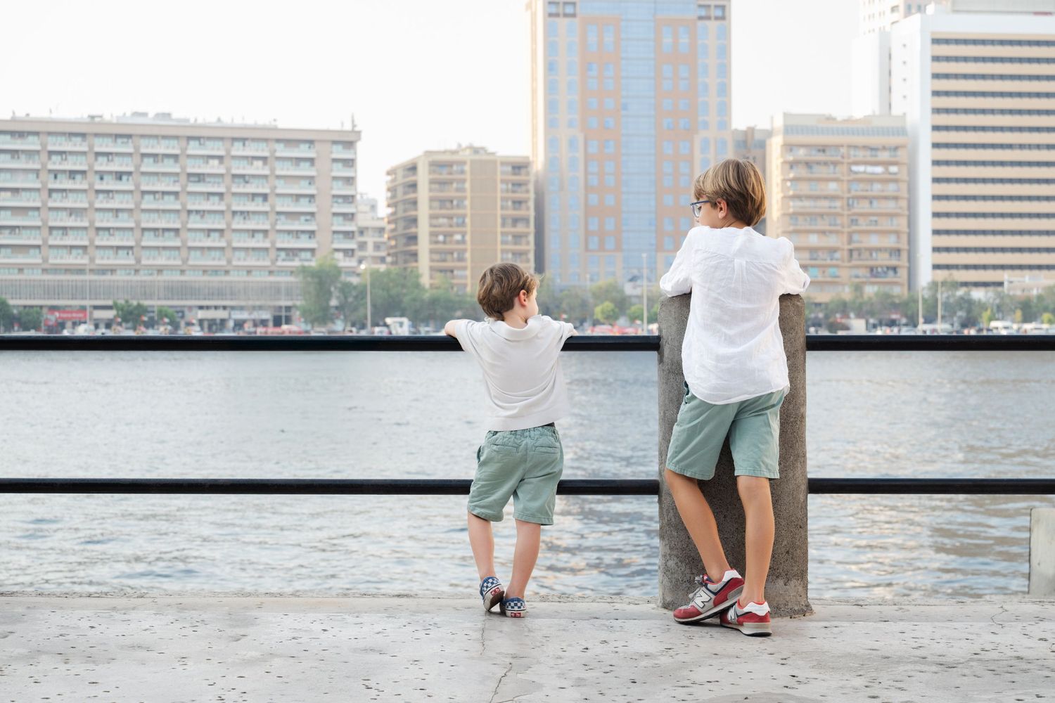 Two people standing together looking at city skyline view from balcony or rooftop.