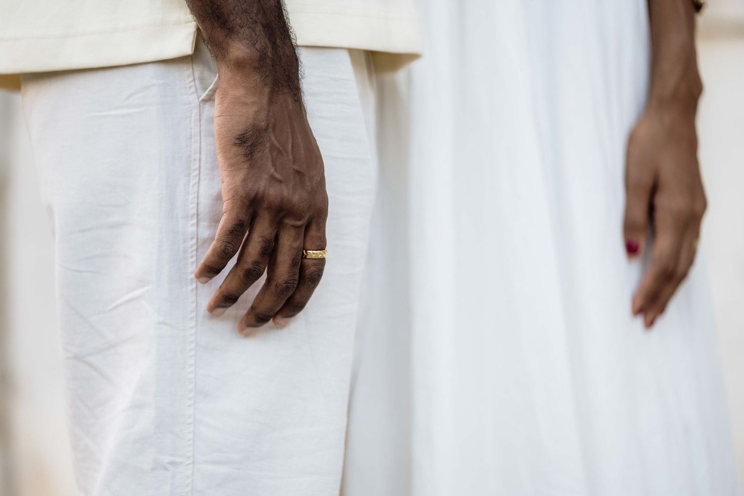 Close-up detail of hands against white clothing in an artistic composition.