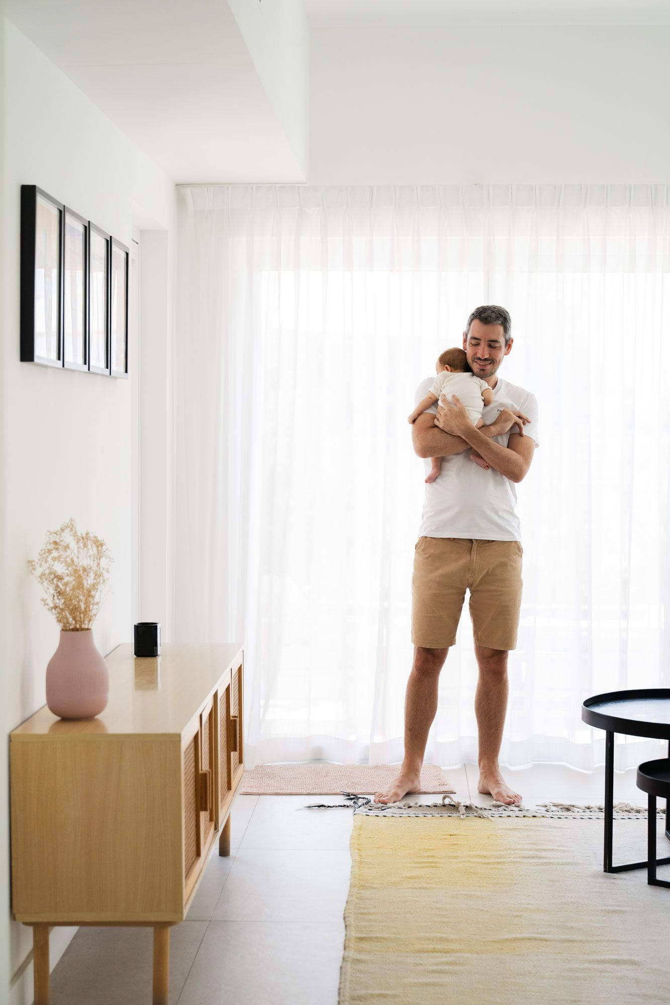 Father holding newborn baby in mimalist living room