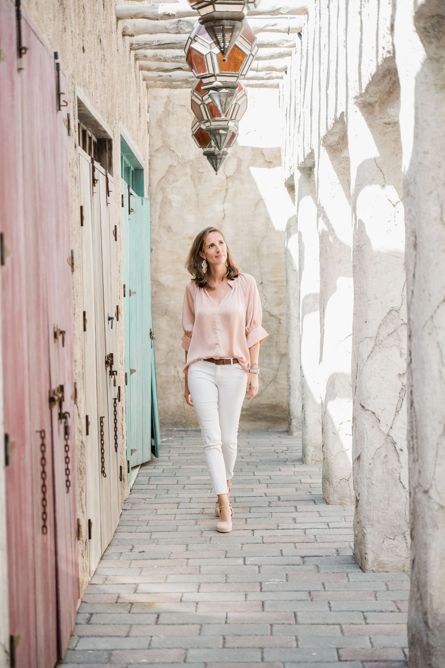 Person walking through pastel-colored hallway with arched doorways and textured walls.