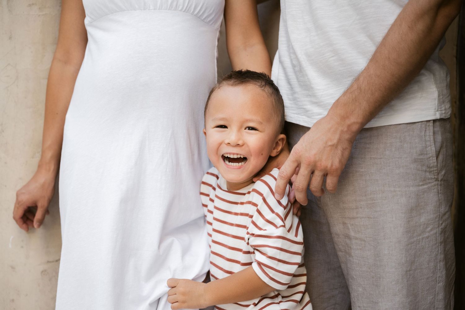 Series of candid family moments against a white stone wall.