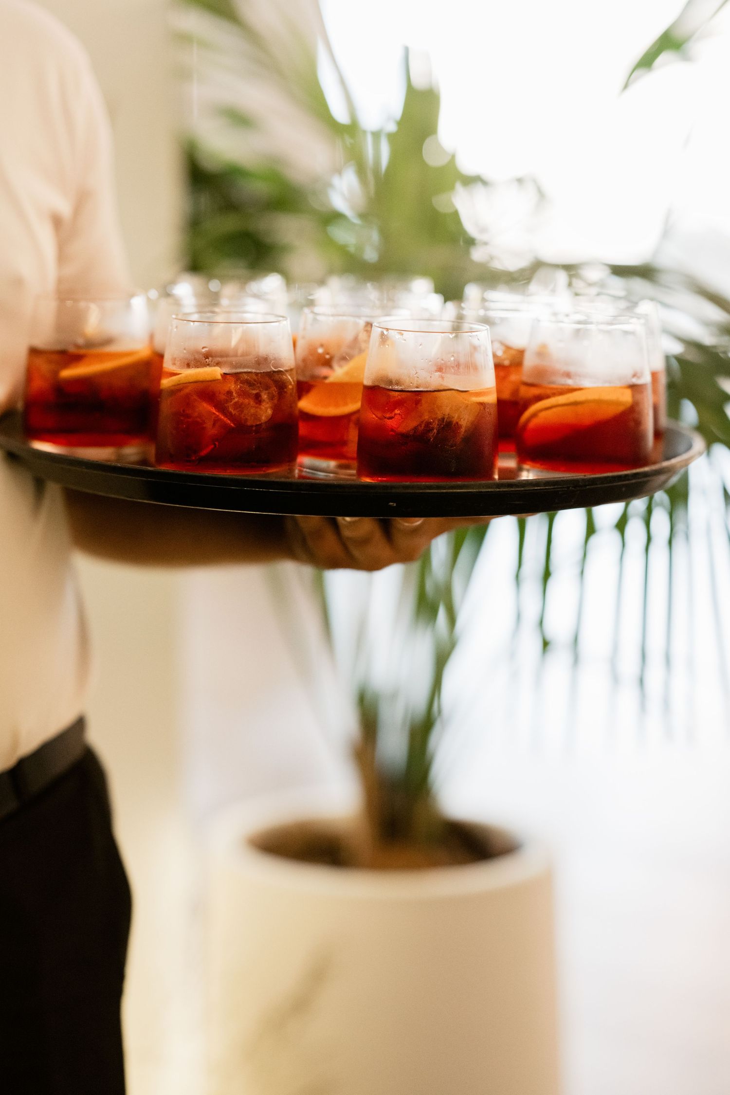 Row of amber-colored cocktails served on dark tray at luxury event.