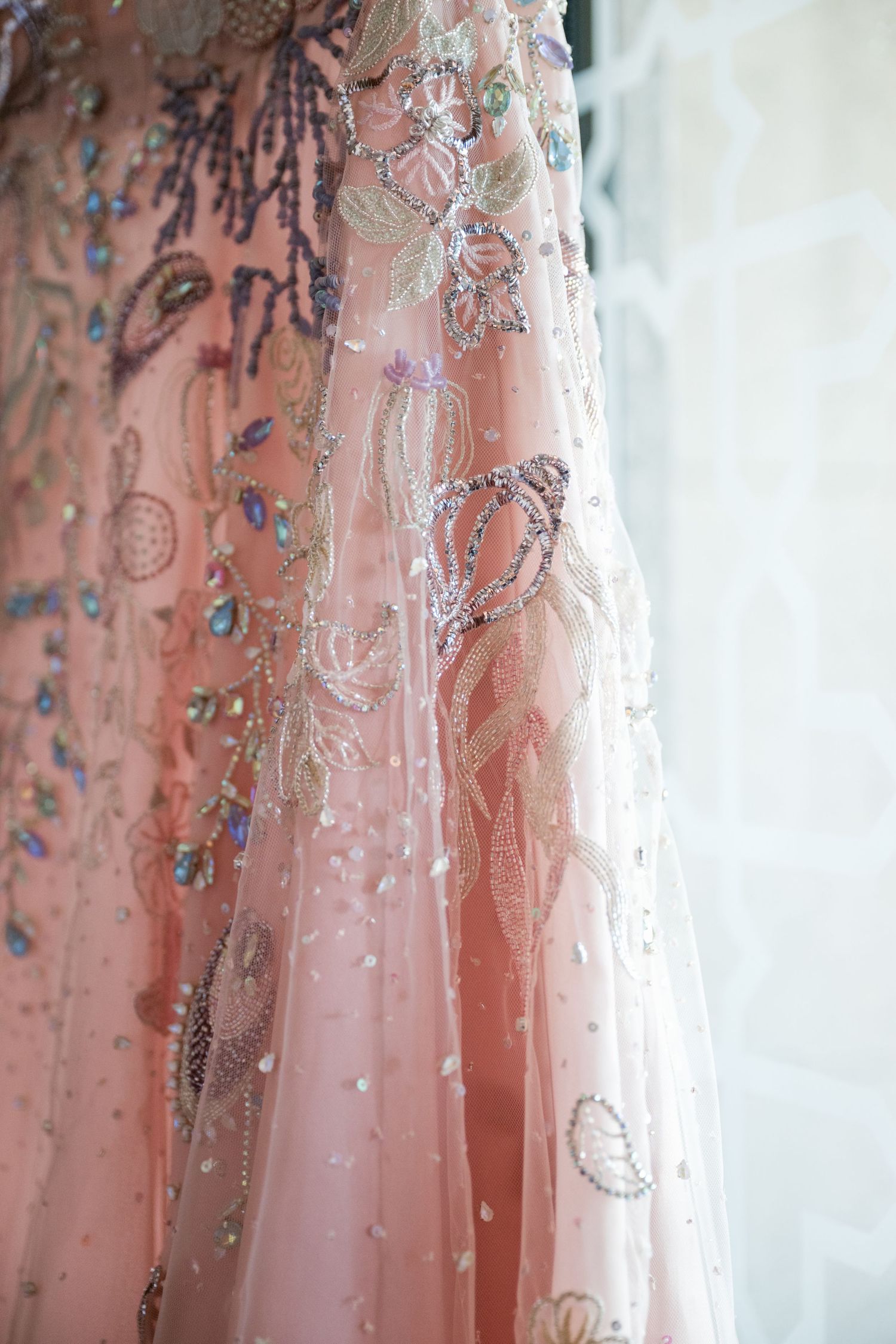 Close-up of a blush pink gown with sparkling beaded details and embroidery.