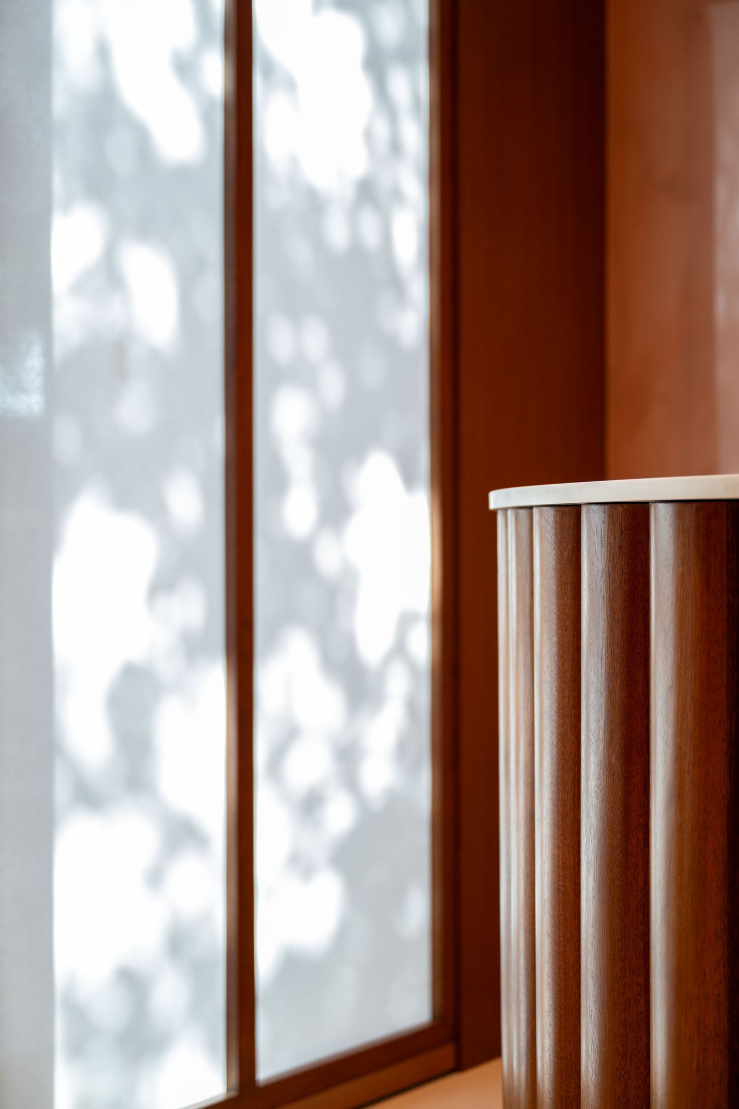 Row of tall windows with wooden frames casting shadow patterns on white walls.