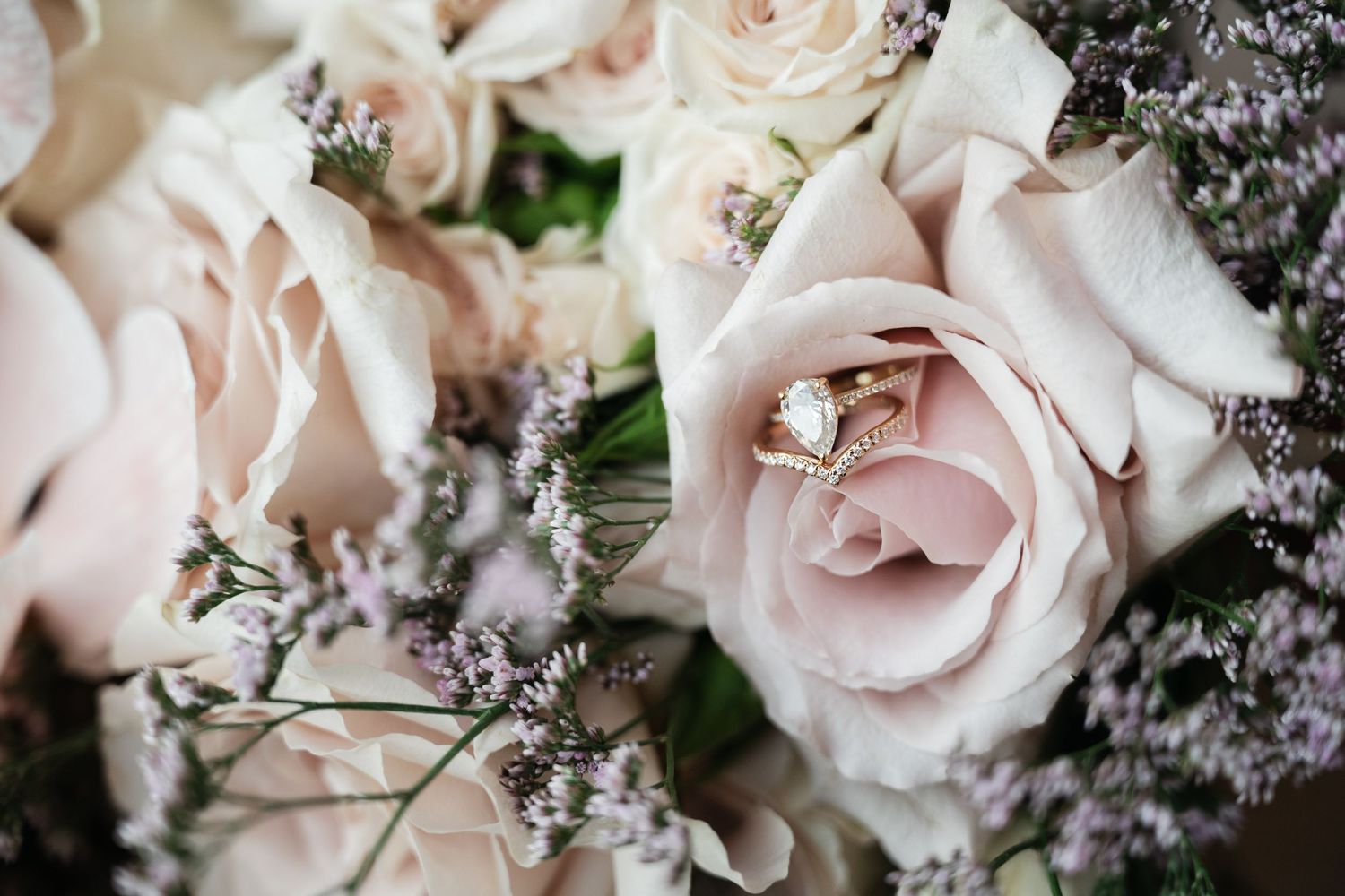 Delicate pink roses and purple flowers arranged in an elegant wedding bouquet.