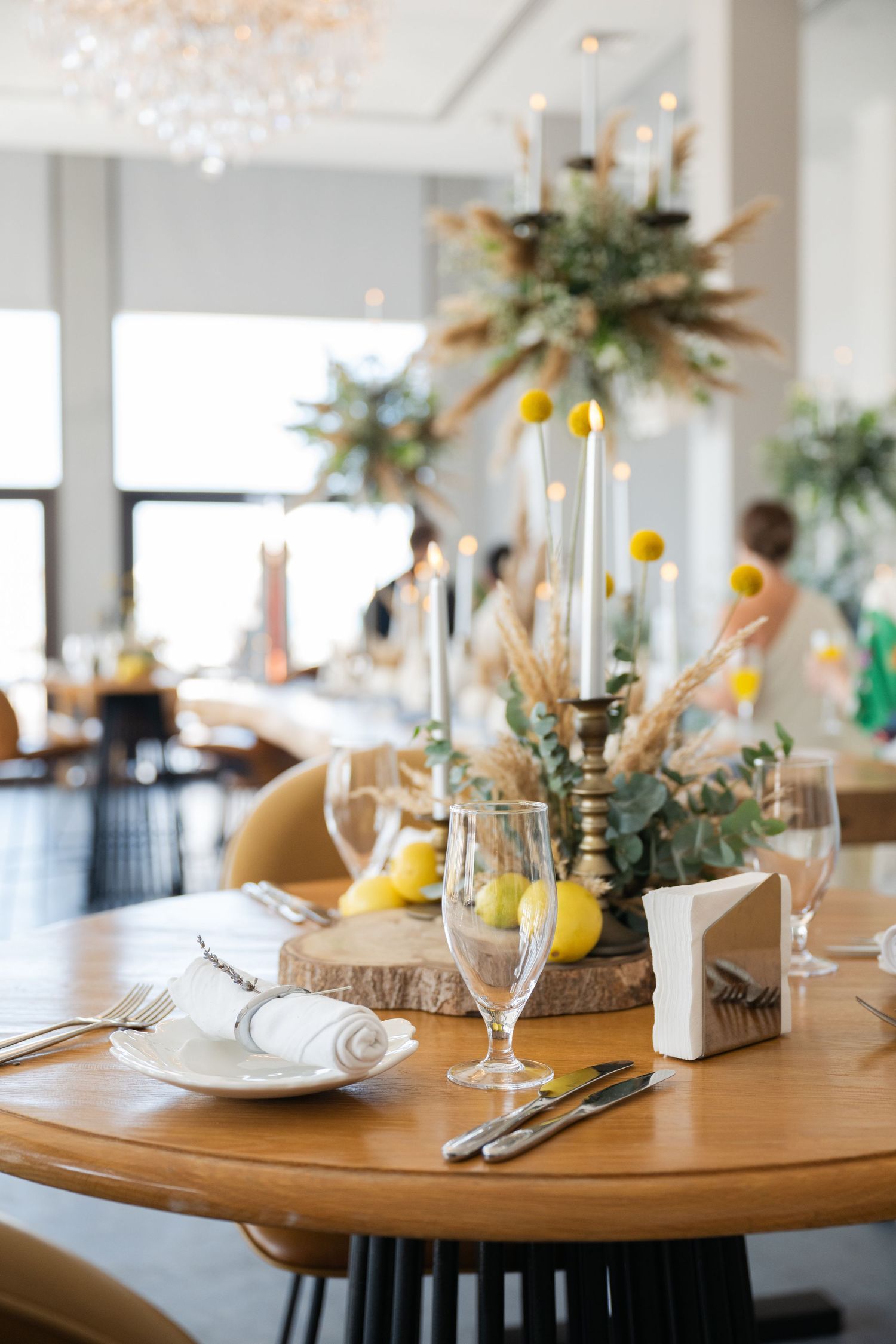 Wedding reception table settings with lemons, candles, and rustic wooden elements.